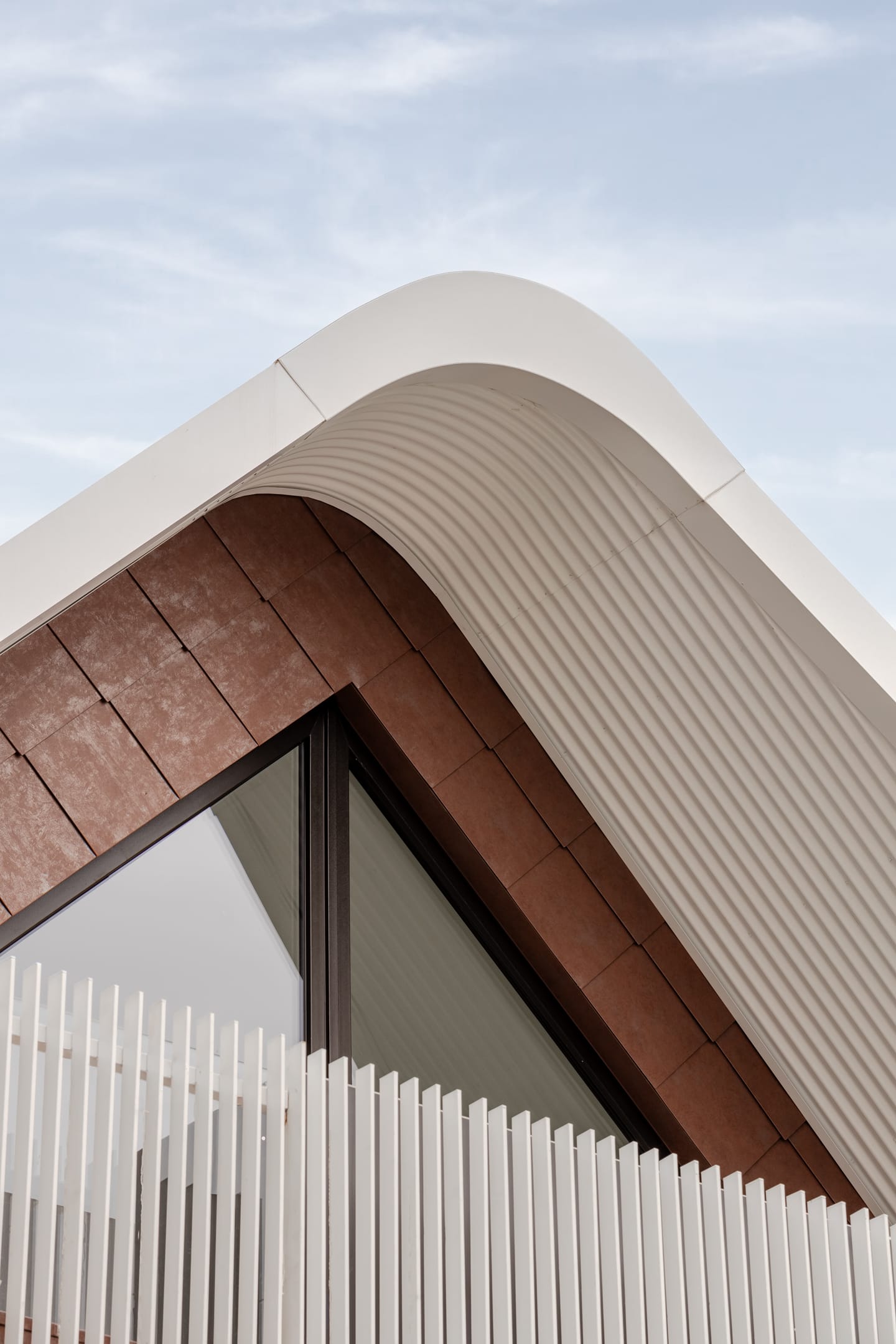 TREE HOUSE by R Architecture. Photography by CM Photography. Close up of roof pitch with brown brick wall time with black framed window and white roof lines.