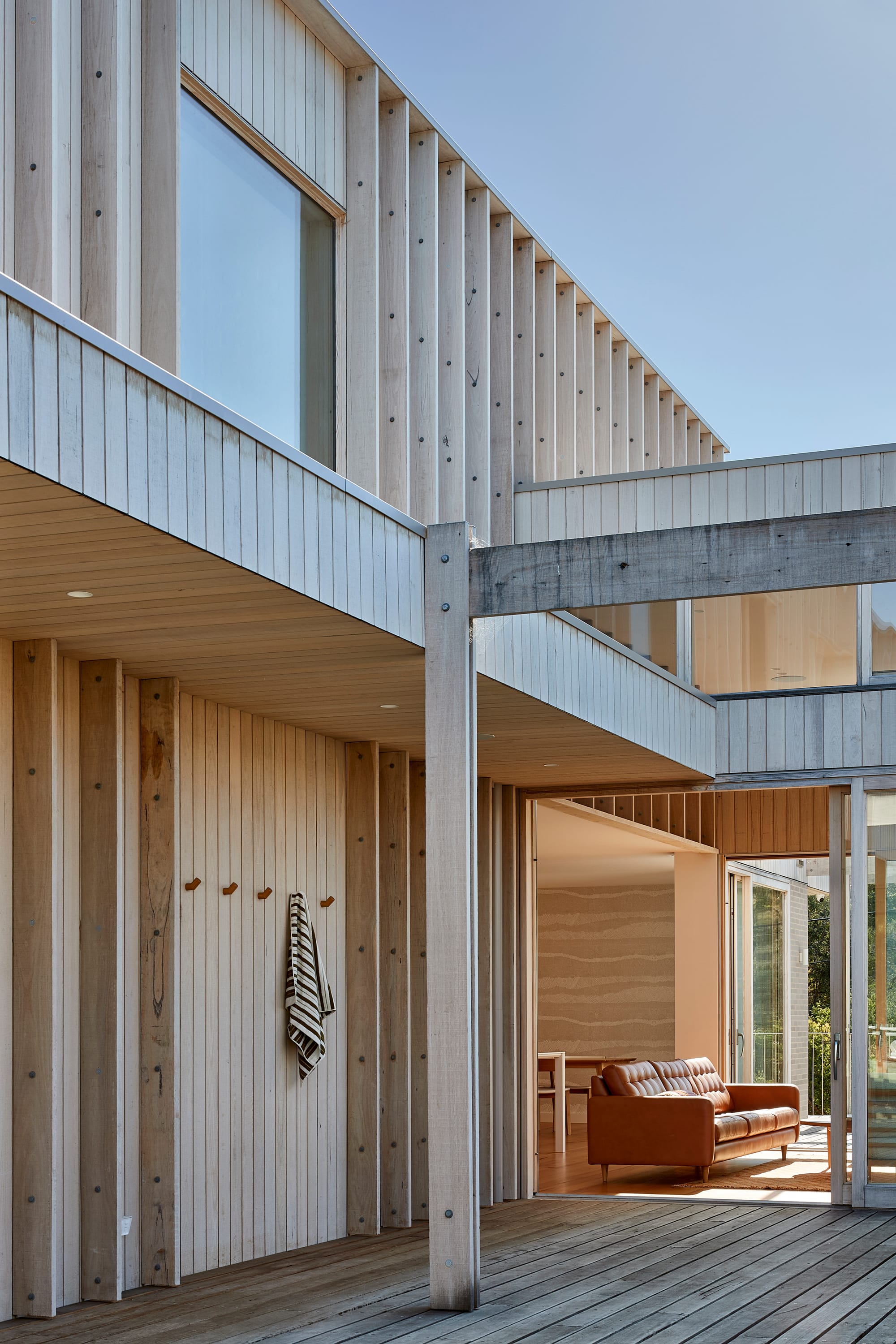 The Blairgowrie Beach Club by Bower Architecture & Interiors. Photography by Shannon McGrath. A wooden patio space with a wall with hangers for towers.