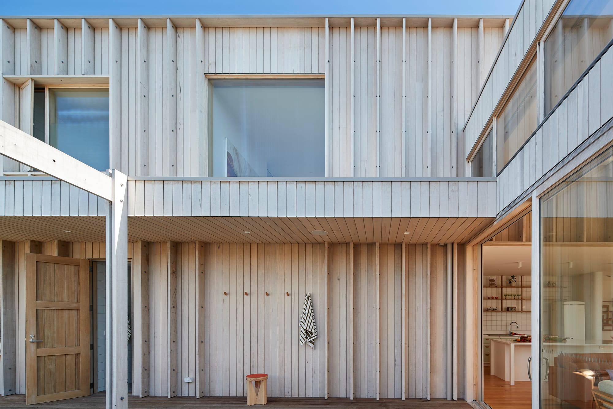 The Blairgowrie Beach Club by Bower Architecture & Interiors. Photography by Shannon McGrath. Corridor with wooden floor with painting hung against the wall.