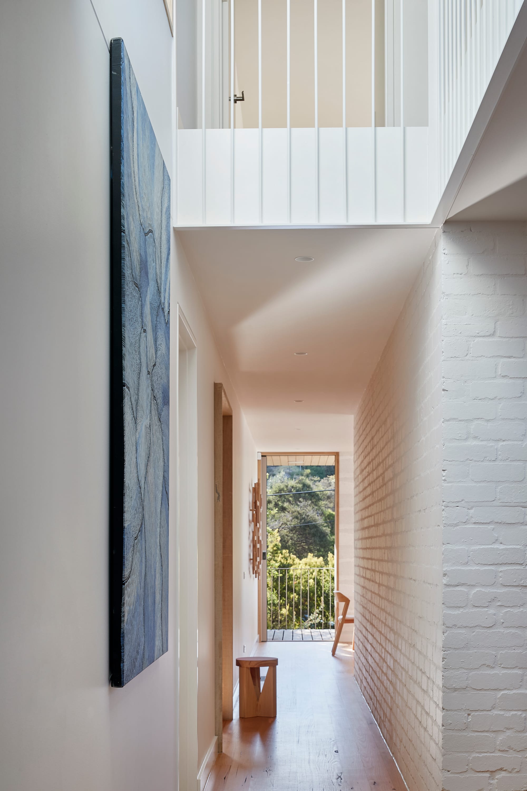 The Blairgowrie Beach Club by Bower Architecture & Interiors. Photography by Shannon McGrath. Corridor with wooden floor with painting hung against the wall.