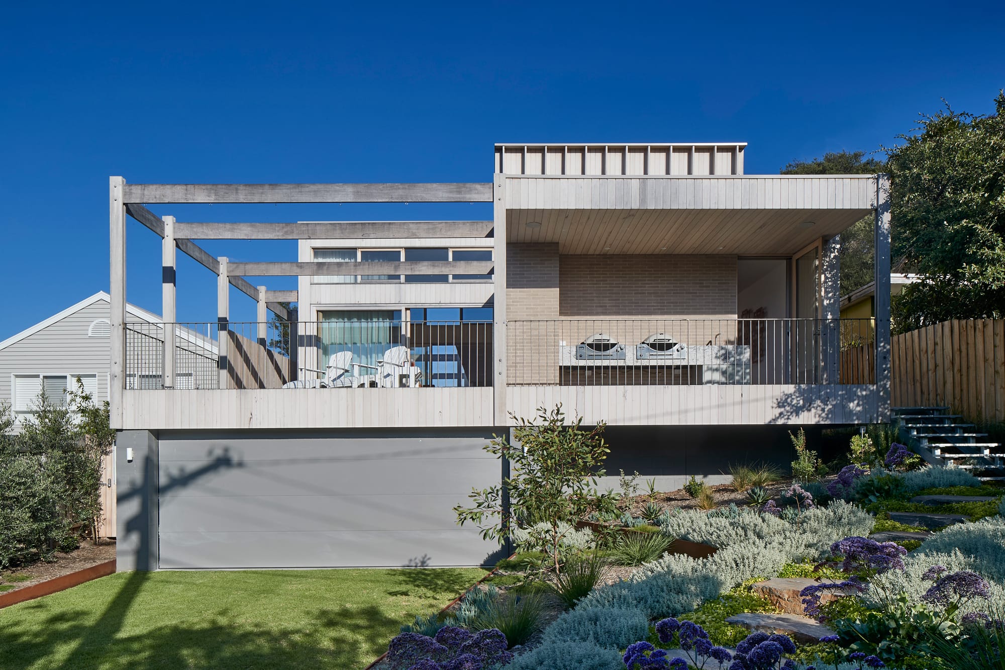 The Blairgowrie Beach Club by Bower Architecture & Interiors. Photography by Shannon McGrath. Front view of two storey building with a terrace and front yard.