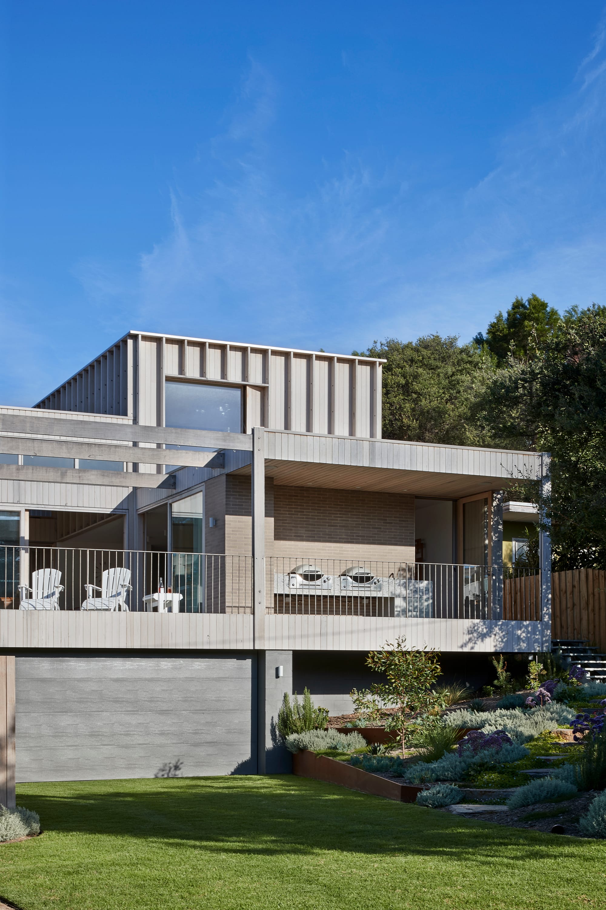 The Blairgowrie Beach Club by Bower Architecture & Interiors. Photography by Shannon McGrath. Close up view of a house with balcony with wooden cladding and entrance on side.