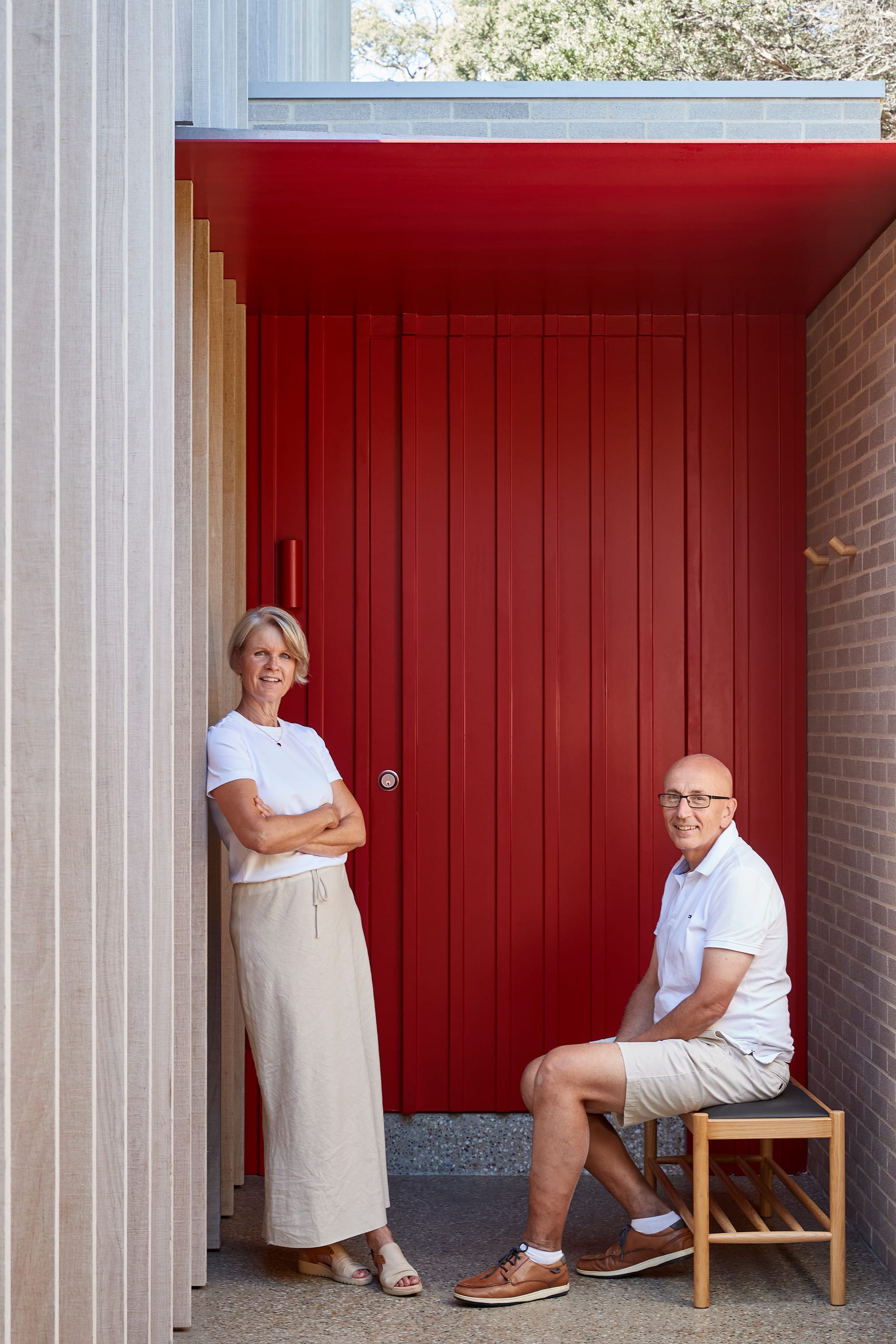 The Blairgowrie Beach Club by Bower Architecture & Interiors. Photography by Shannon McGrath. Two people; one seating and other one standing infront of red door.