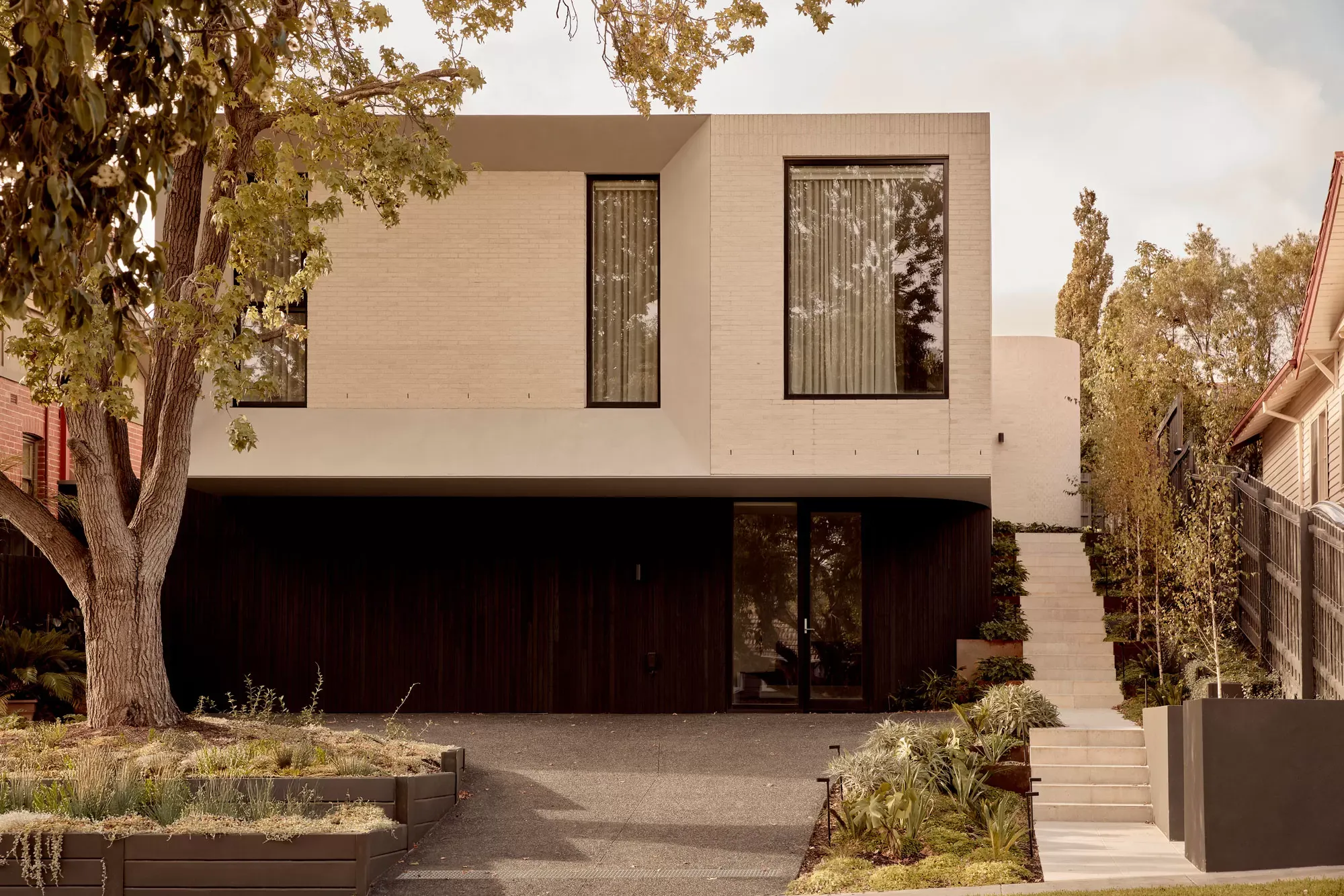Brixton by Cera Stribley. Photography by Martina Gemmola. Two-storey modern house with light brick upper level and dark timber cladding below.