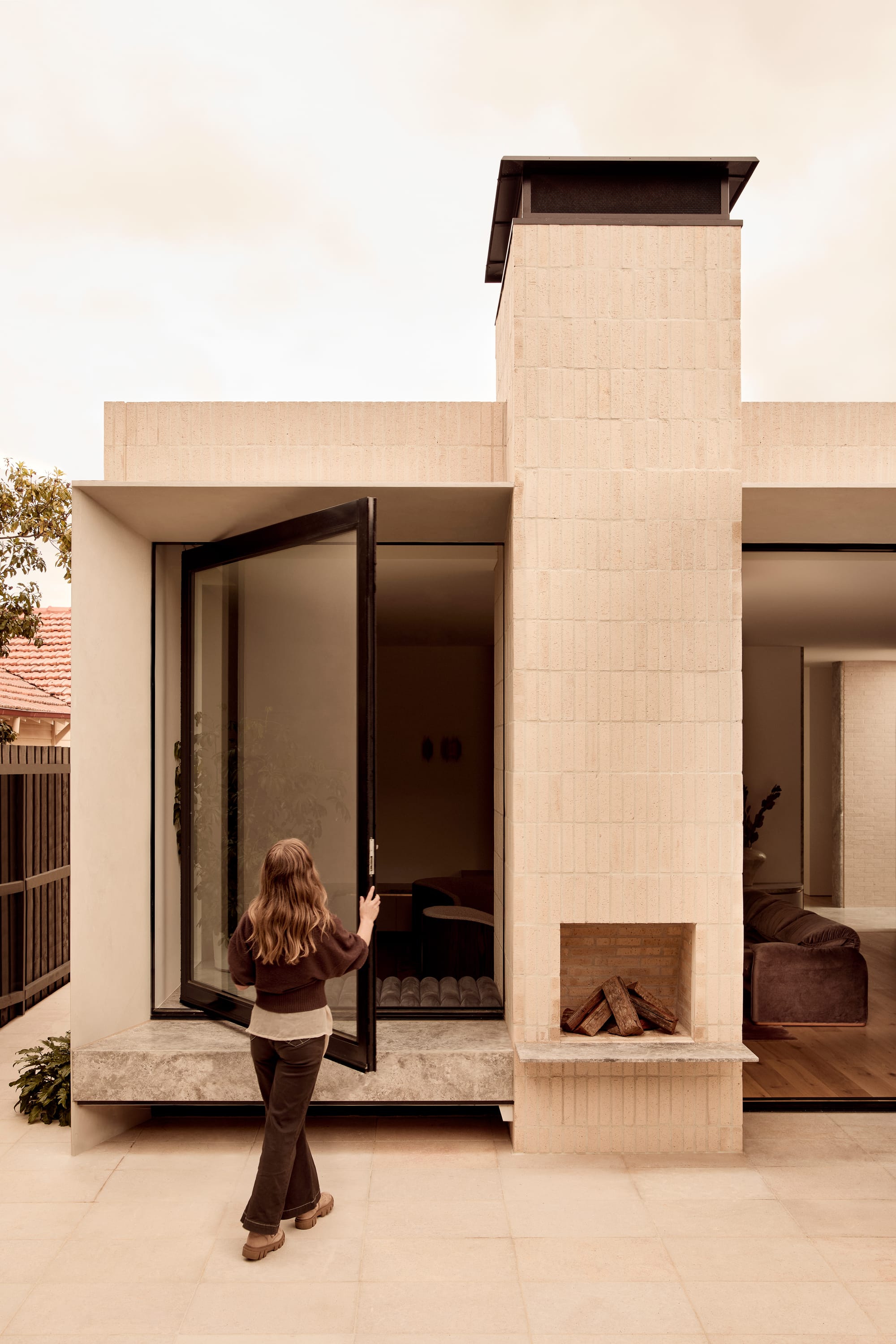 Brixton by Cera Stribley. Photography by Martina Gemmola. A person closing big window beside the fireplace in the wall.