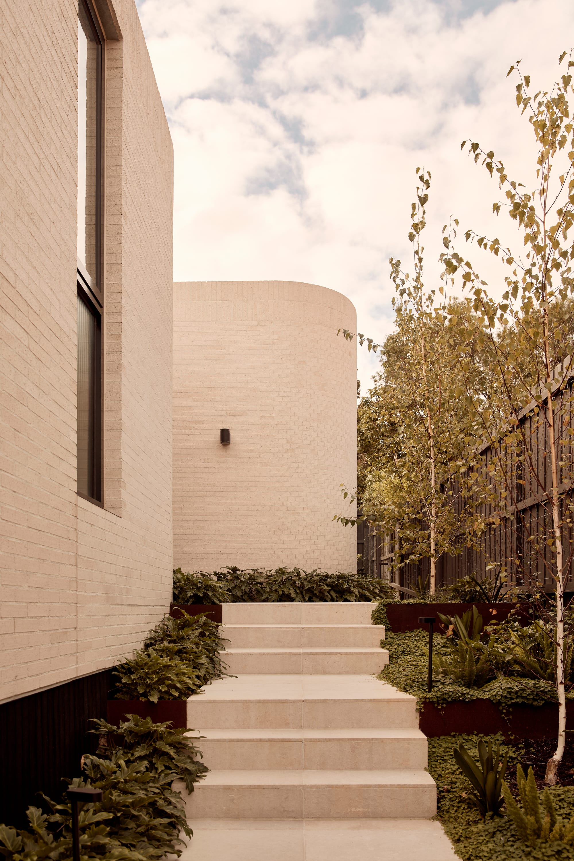 Brixton by Cera Stribley. Photography by Martina Gemmola. Steps leading to structure with curved wall surrounded by greenaries.