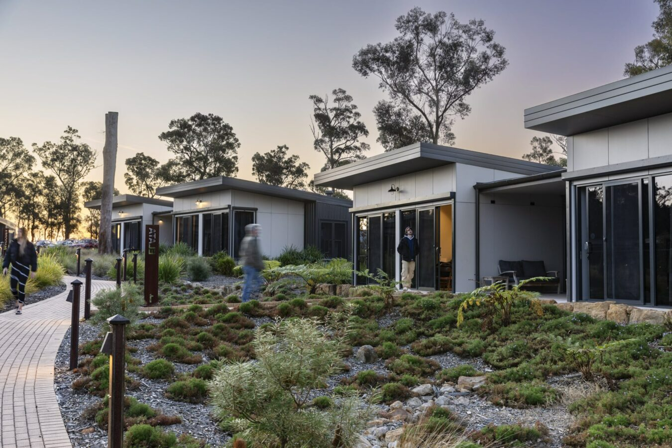 Kangaroo Valley Retreat by Edmiston Jones. Photographer undisclosed. Multiple sef-contained accommodation homes connected by a brick footpath through a low native garden. 