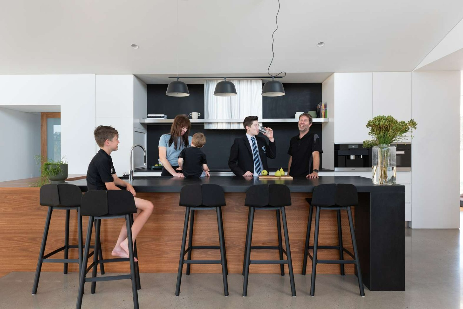 The Blairgowrie Beach Club by Bower Architecture & Interiors. Photography by Shannon McGrath. Woman sitting at white island bench.