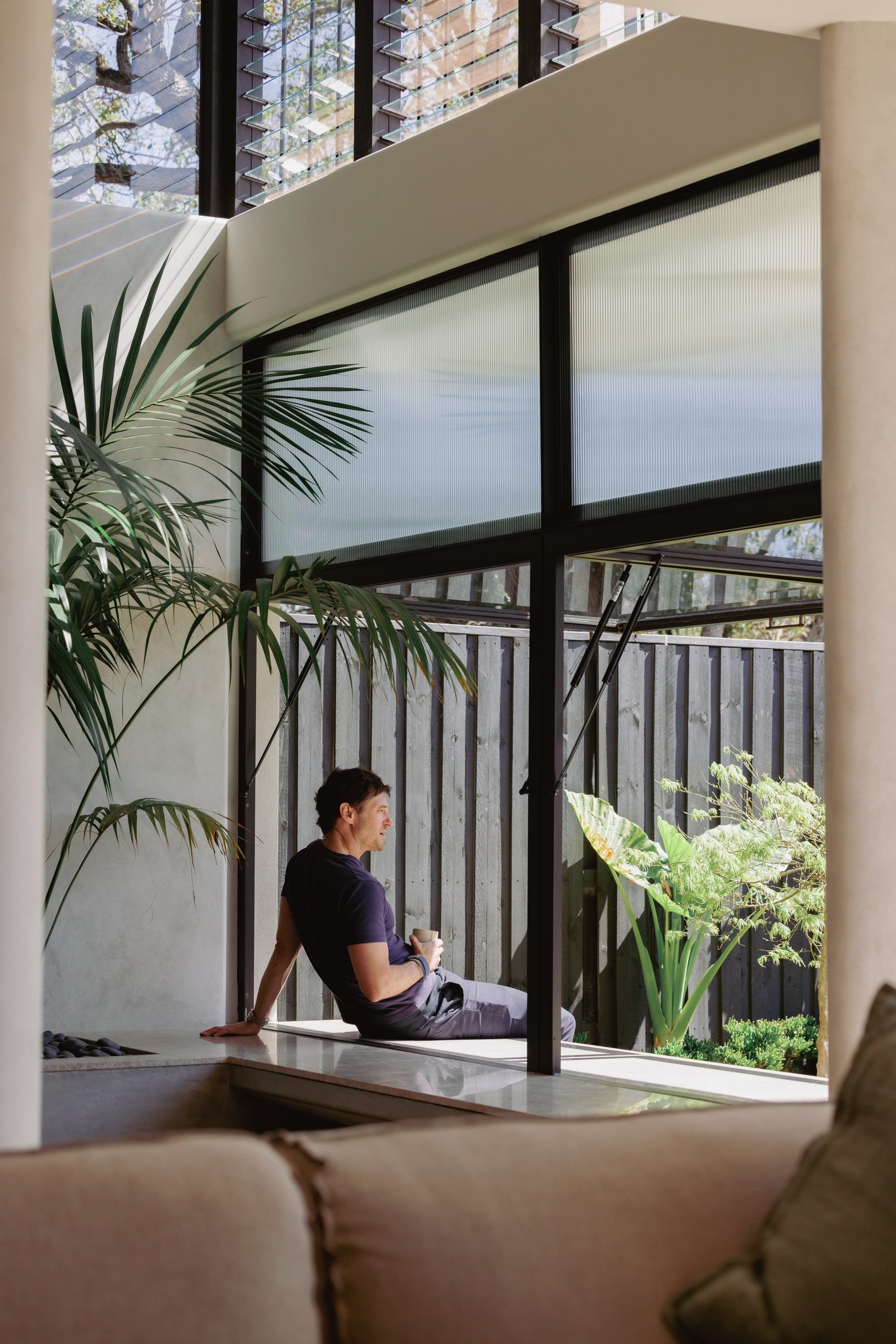 Little Birch by buck&simple. Interior shot showing a man sitting at the window seat drinking a coffee.