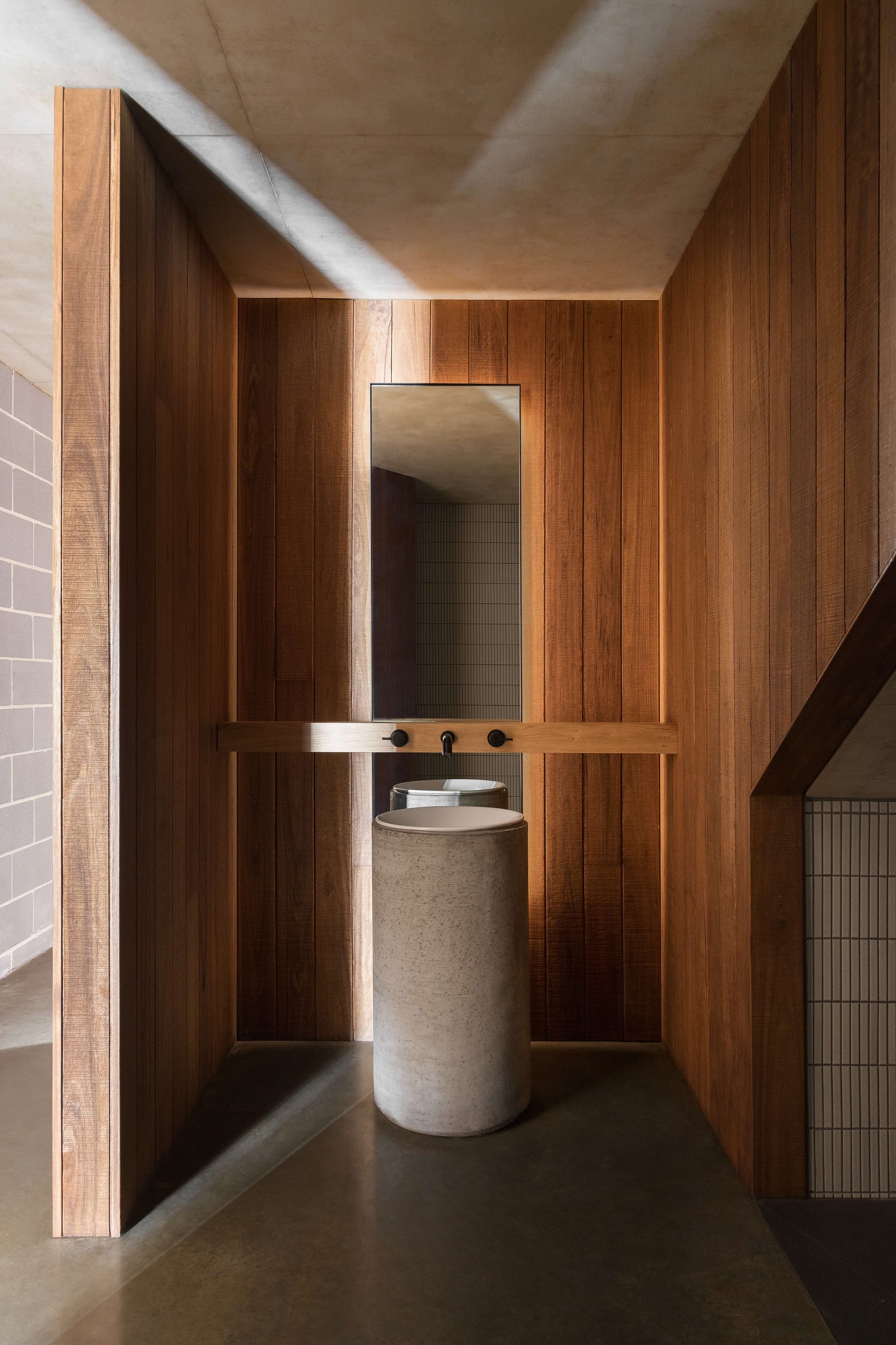 Merricks House by Aktis Architects. Photography by&nbsp;Timothy Kaye. Minimalist bathroom with vertical timber walls, cylindrical concrete basin, wall-mounted tapware, and a tall mirror.