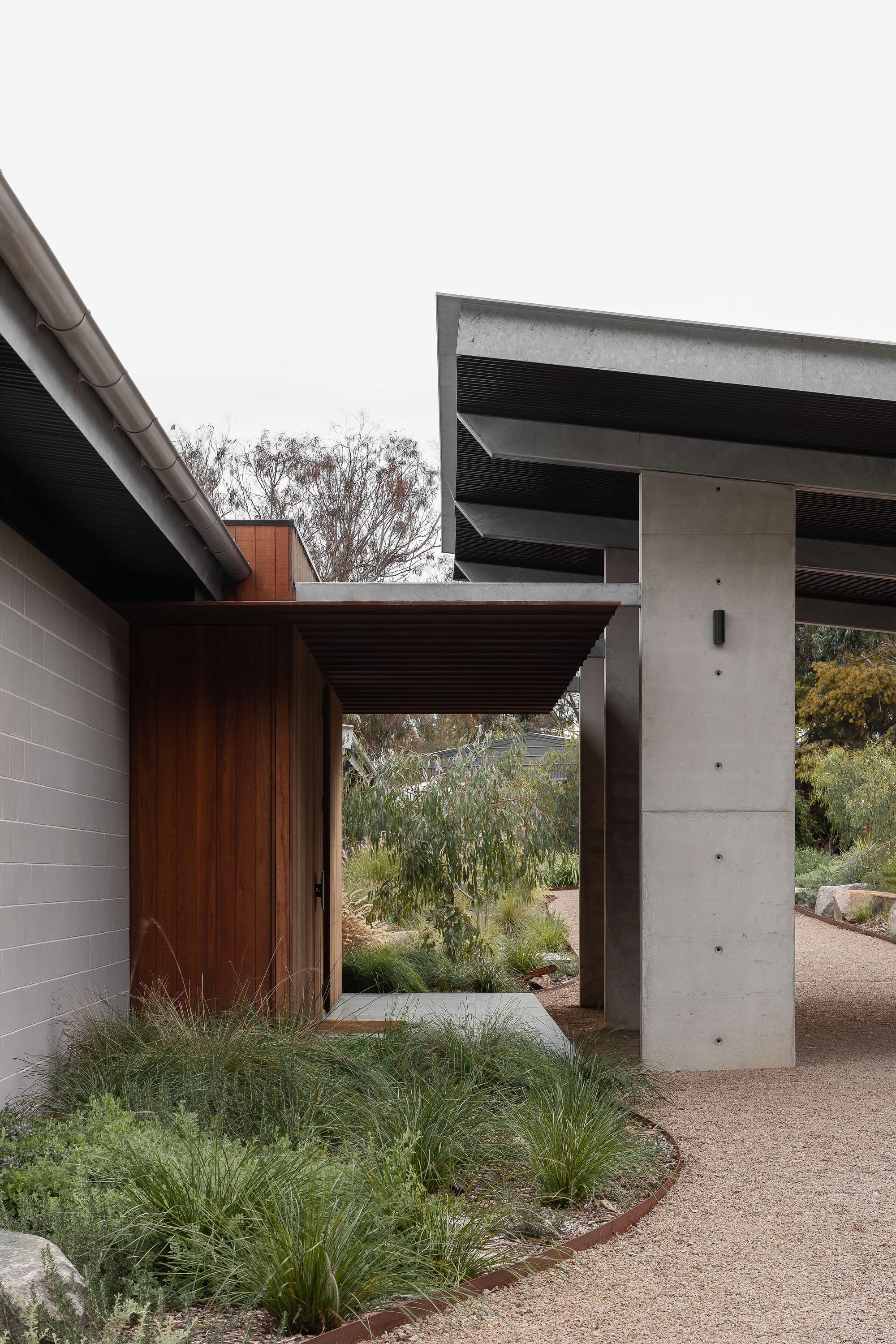 Merricks House by Aktis Architects. Photography by&nbsp;Timothy Kaye. Architectural detail of a modern entry with timber cladding, concrete columns, and steel canopy set within native landscaping.