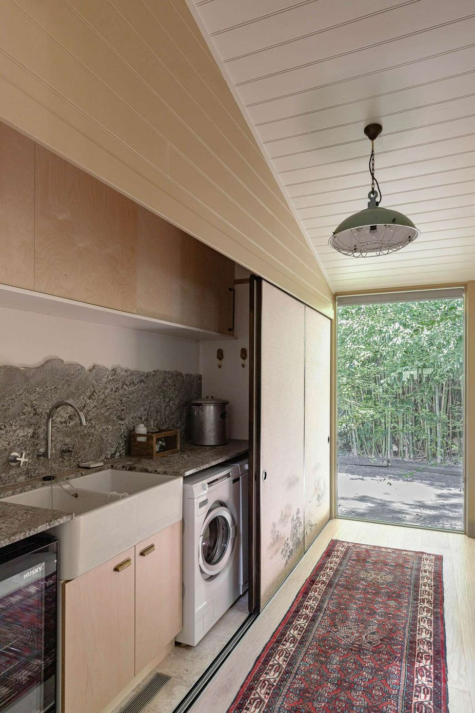 Redbarn by Robertson Collectif. Photography by Life In Still. Galley style laundry with timber cabinets, farm-style sink, granite countertop and splashback and Persian hallway runner rug. 