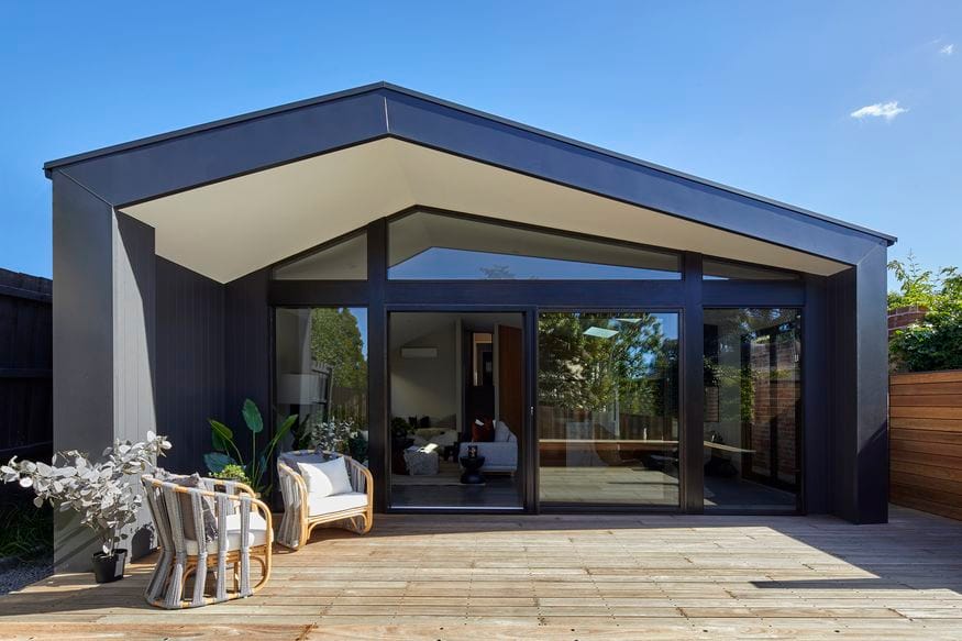 Glen Iris Home by Samuel Architecture. Photography by Dave Kulesza. Contemporary pavilion-style extension with angular pitched roof, black steel frame, and full-height glazing opening to a timber deck.