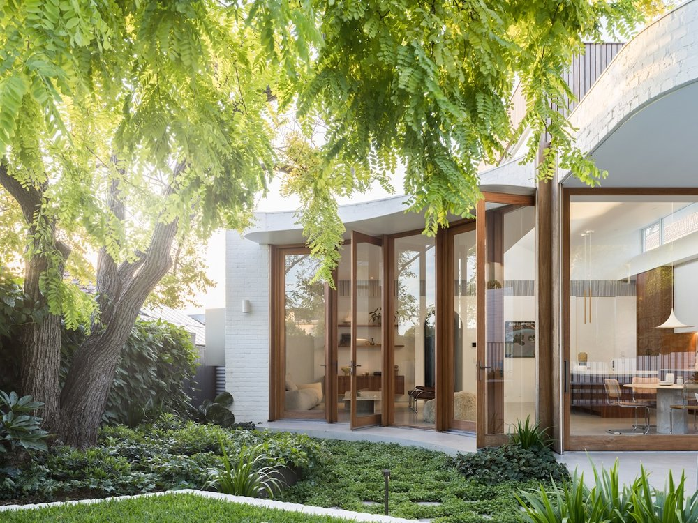 MR. ROBIN and MRS. ROSE by Brcar Morony Architecture. Photography by Justin Alexander.Contemporary home exterior with curved architecture, full-height timber-framed glass doors, and a lush garden shaded by mature trees. 