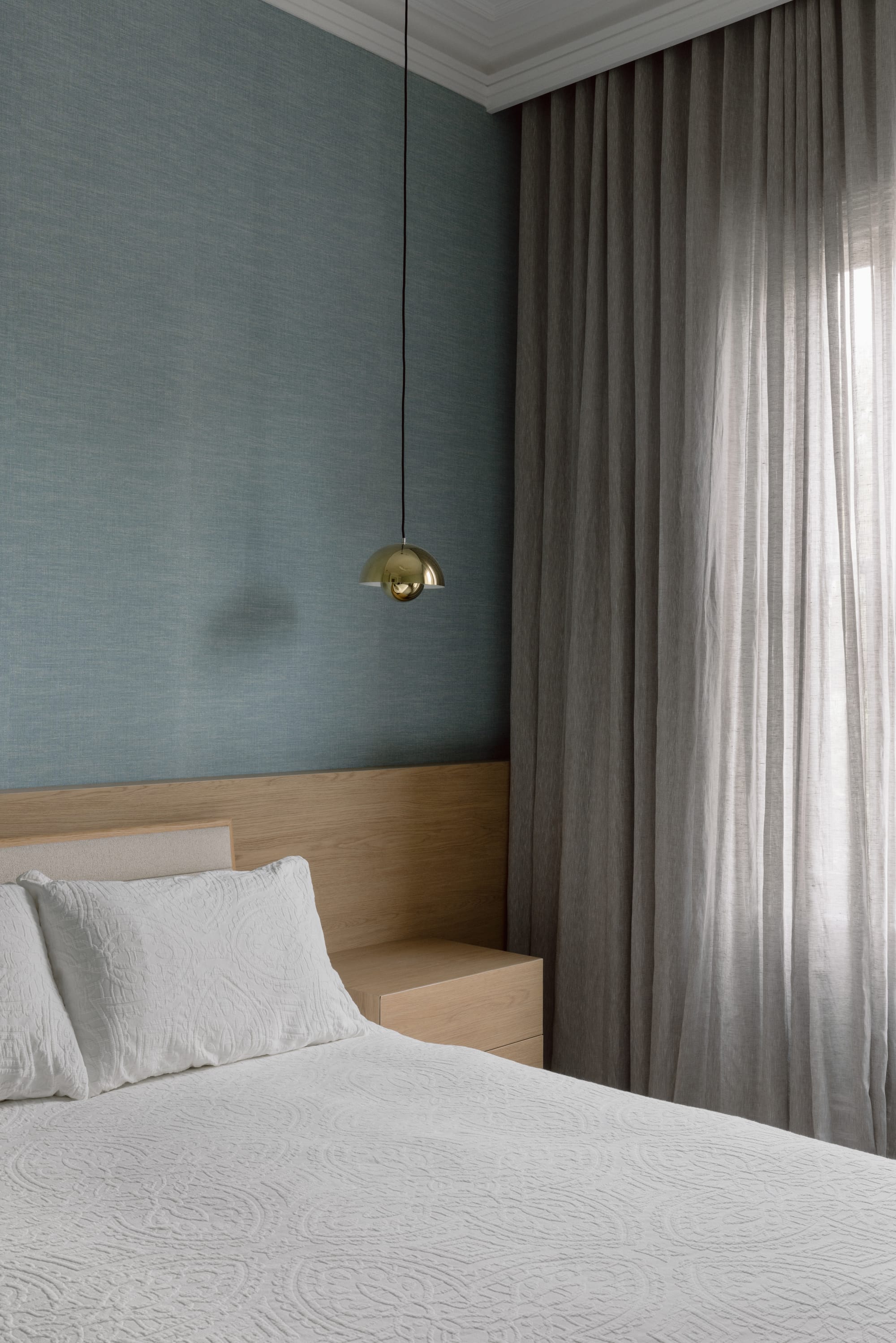 Auburn Residence by Chan Architecture. Photography by Elise Scott. Bedroom with white patterned bedding, timber headboard, blue wallpaper and single bedside pendant light.  