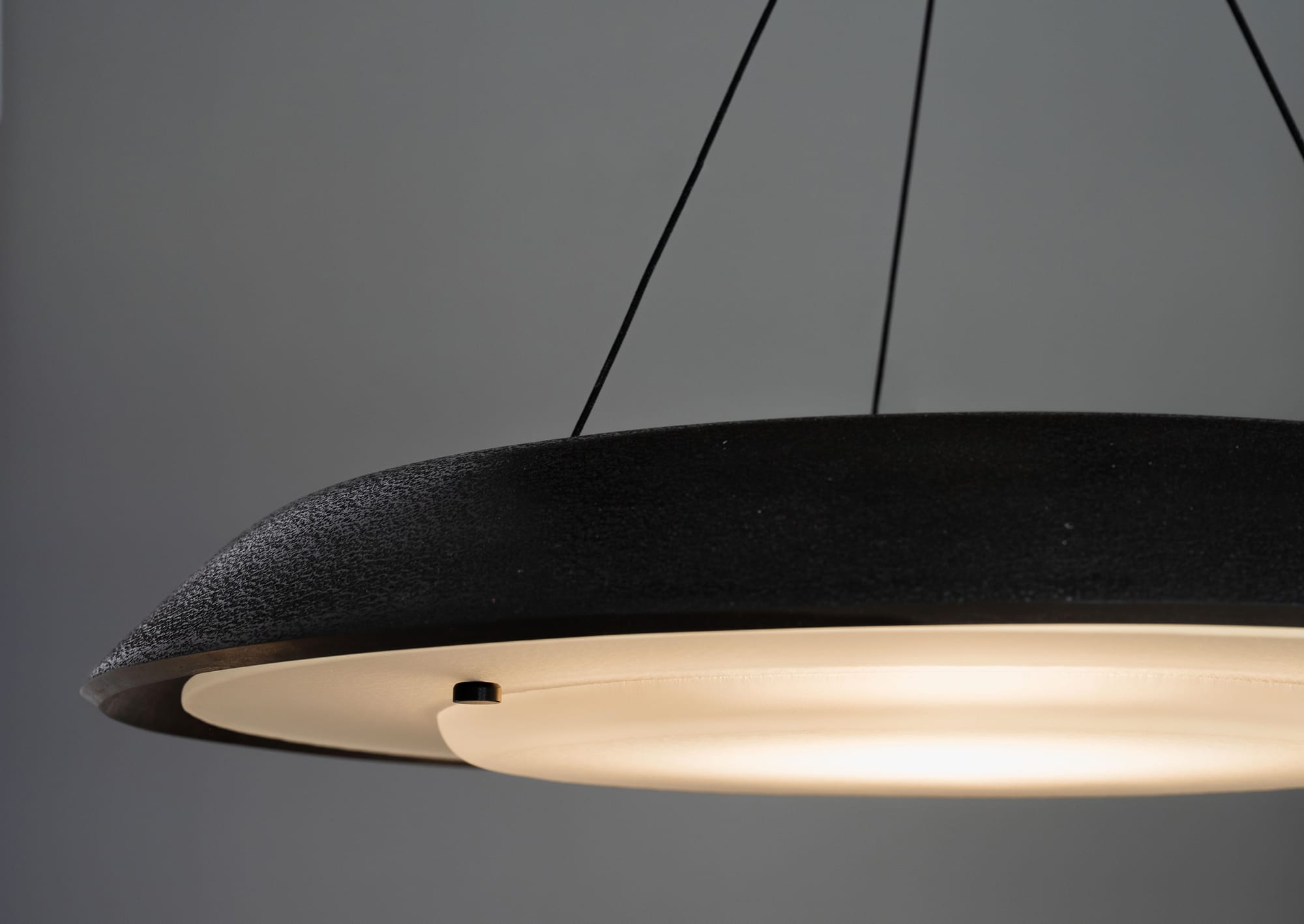 Husk Collection By South Drawn. Photography by Reannon Smith. A close-up of the suspended Husk pendant reveals its textured Zeoform shell and softly diffused glow.