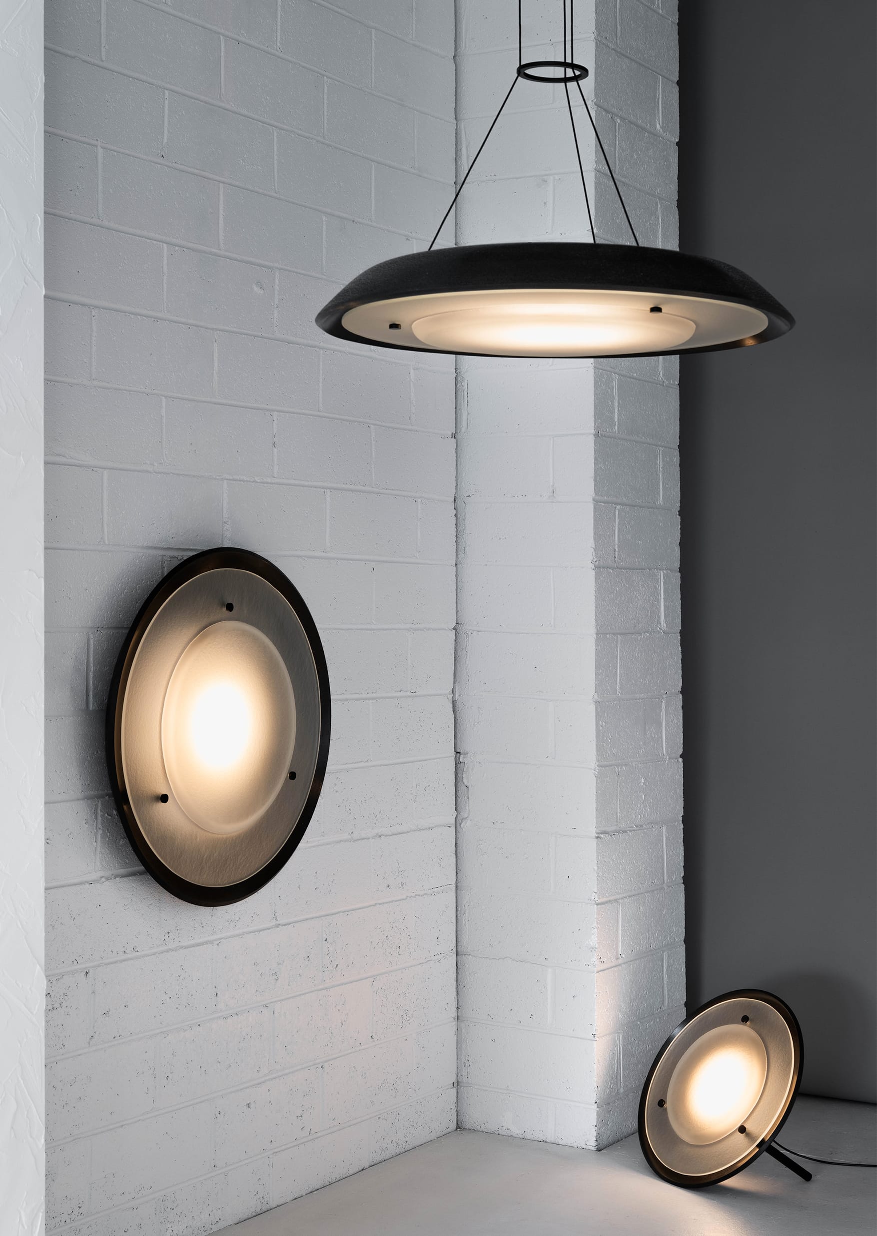 Husk Collection By South Drawn. Photography by Reannon Smith. The black-edged Husk lights create a striking contrast against white brick, offering soft illumination in three sculptural forms.