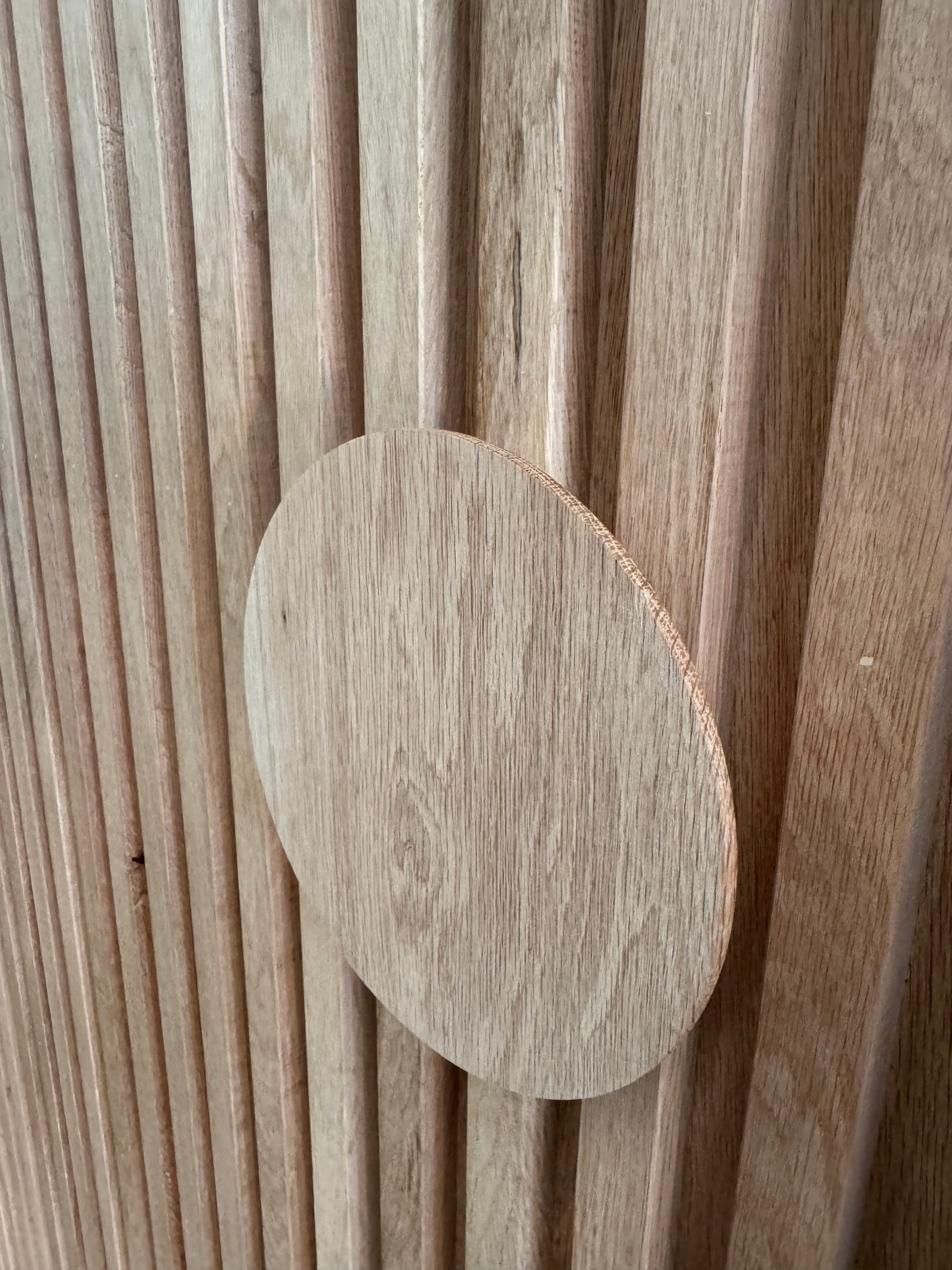 Sunset Joinery. Photography by Sunset Joinery.Close-up of a fluted timber surface with a circular wooden handle detail, showcasing natural grain and craftsmanship.