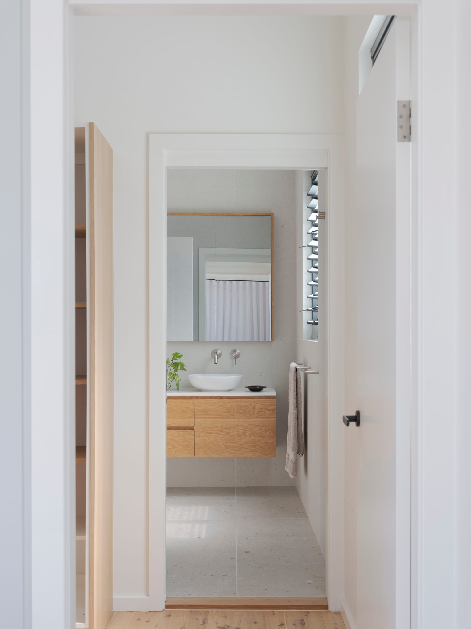 Three Points House by BIJL Architecture. Photography by Tom Ferguson. Minimalist bathroom with timber vanity, vessel basin, mirrored cabinet, and louvred window.
