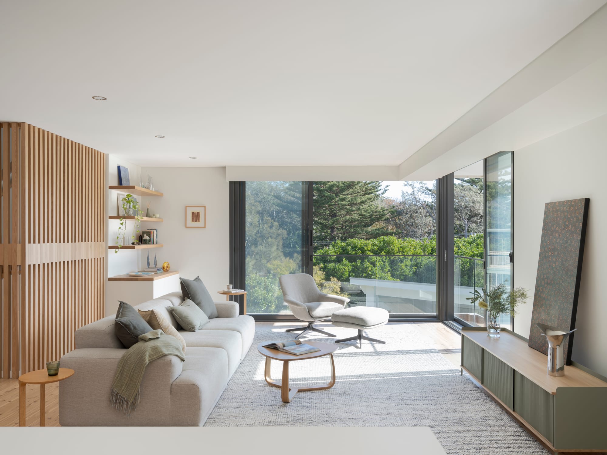 Three Points House by BIJL Architecture. Photography by Tom Ferguson.Bright living room with light furniture, timber accents, and large sliding doors opening to a leafy view.