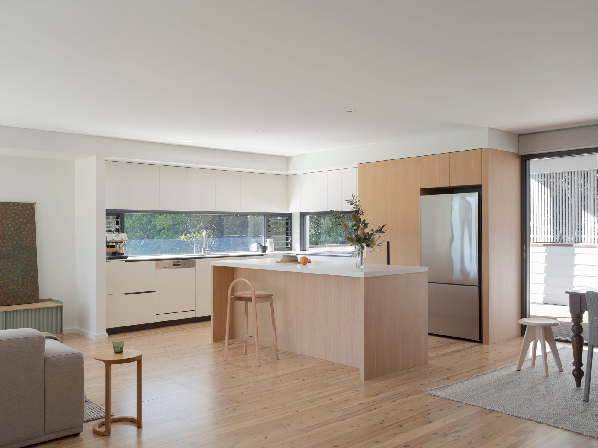 Three Points House by BIJL Architecture. Photography by Tom Ferguson.Minimalist kitchen with light timber cabinetry, a central island, and a wide window splashback overlooking greenery.
