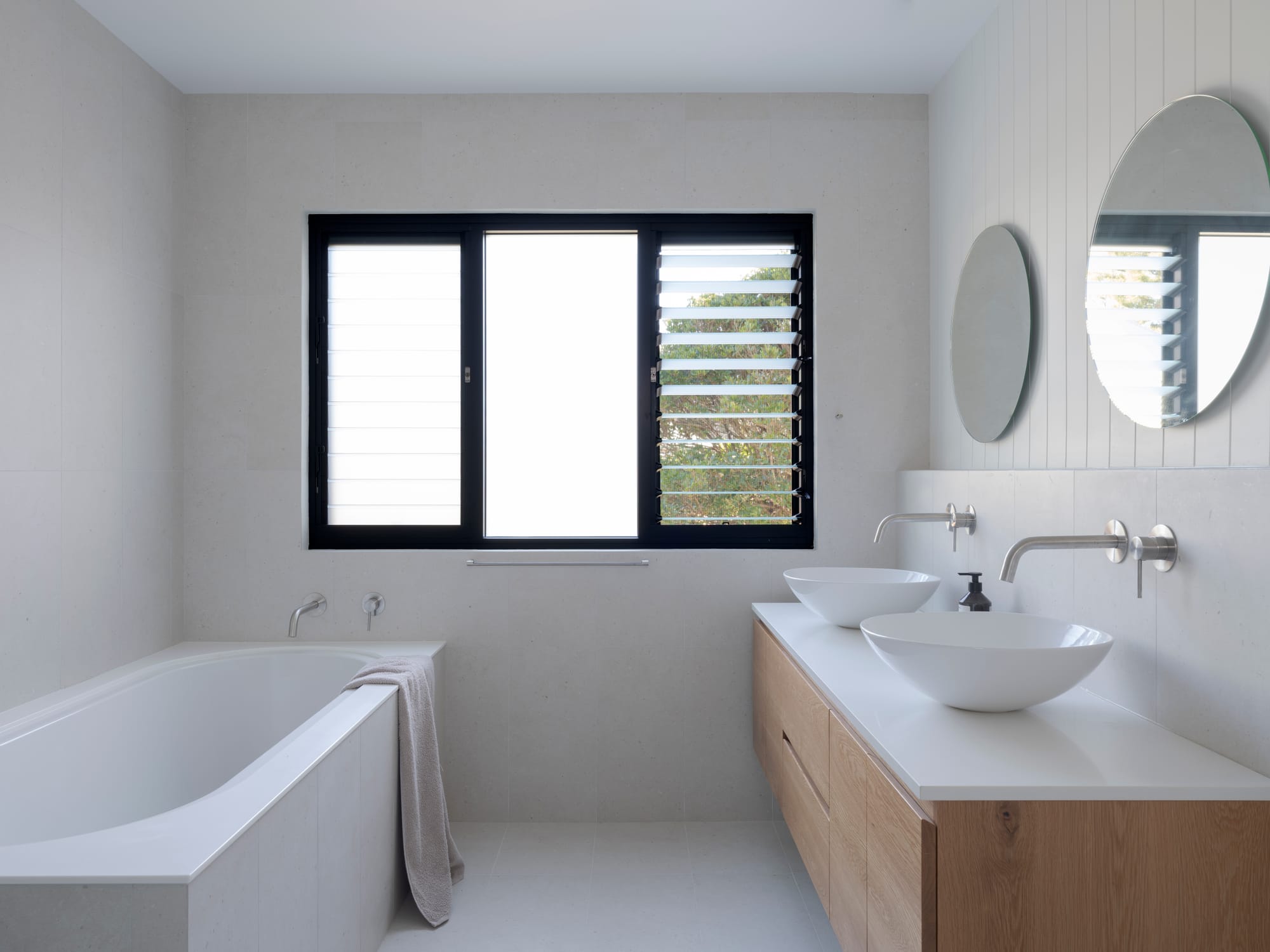 Three Points House by BIJL Architecture. Photography by Tom Ferguson.Contemporary bathroom with built-in bathtub, timber vanity, vessel basins, and louvred window.
