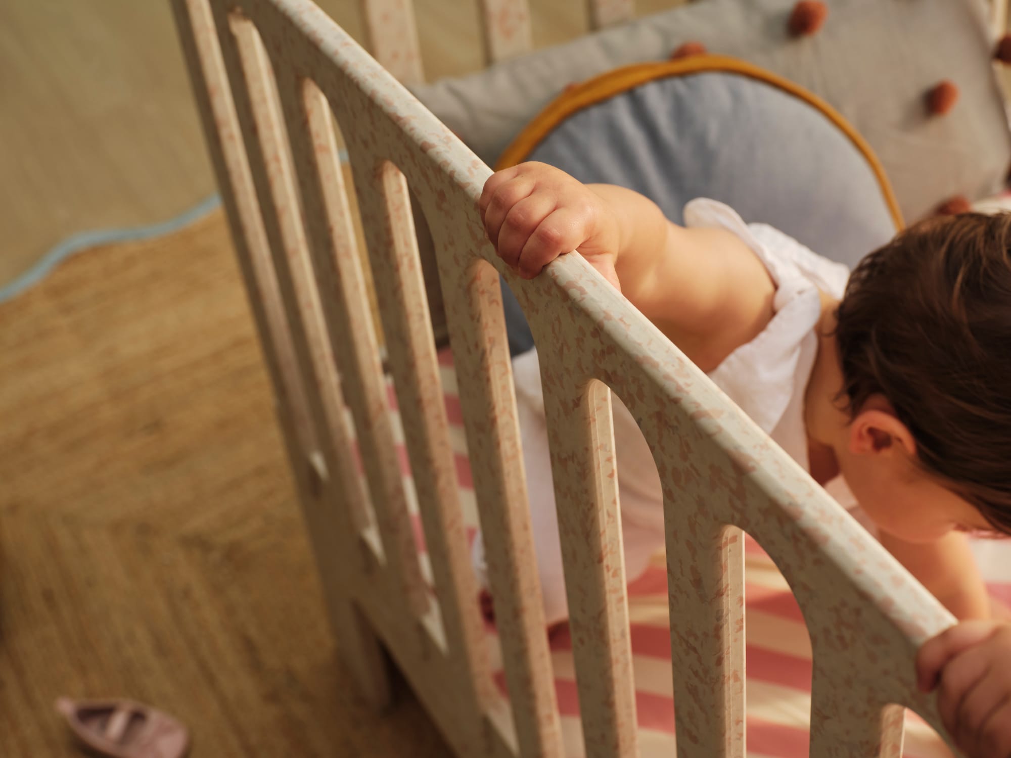 Archie Cot by Seena x Defy in Dalmation Pink. Close up on white and pink speckled cot with white and pink striped mattress cover.
