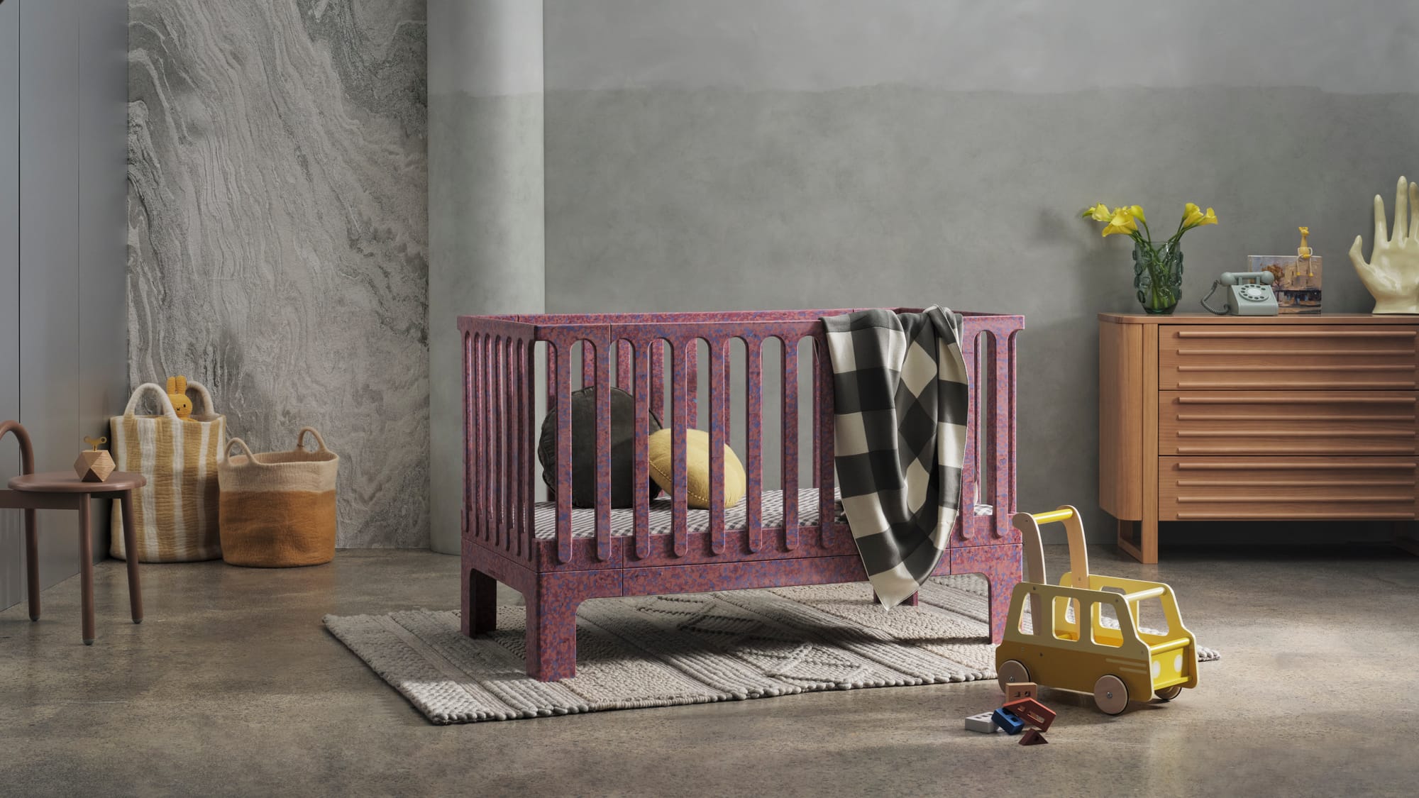 Archie Cot by Seena x Defy in Plum. Purple crib with pink speckles in room with concrete floors and walls.
