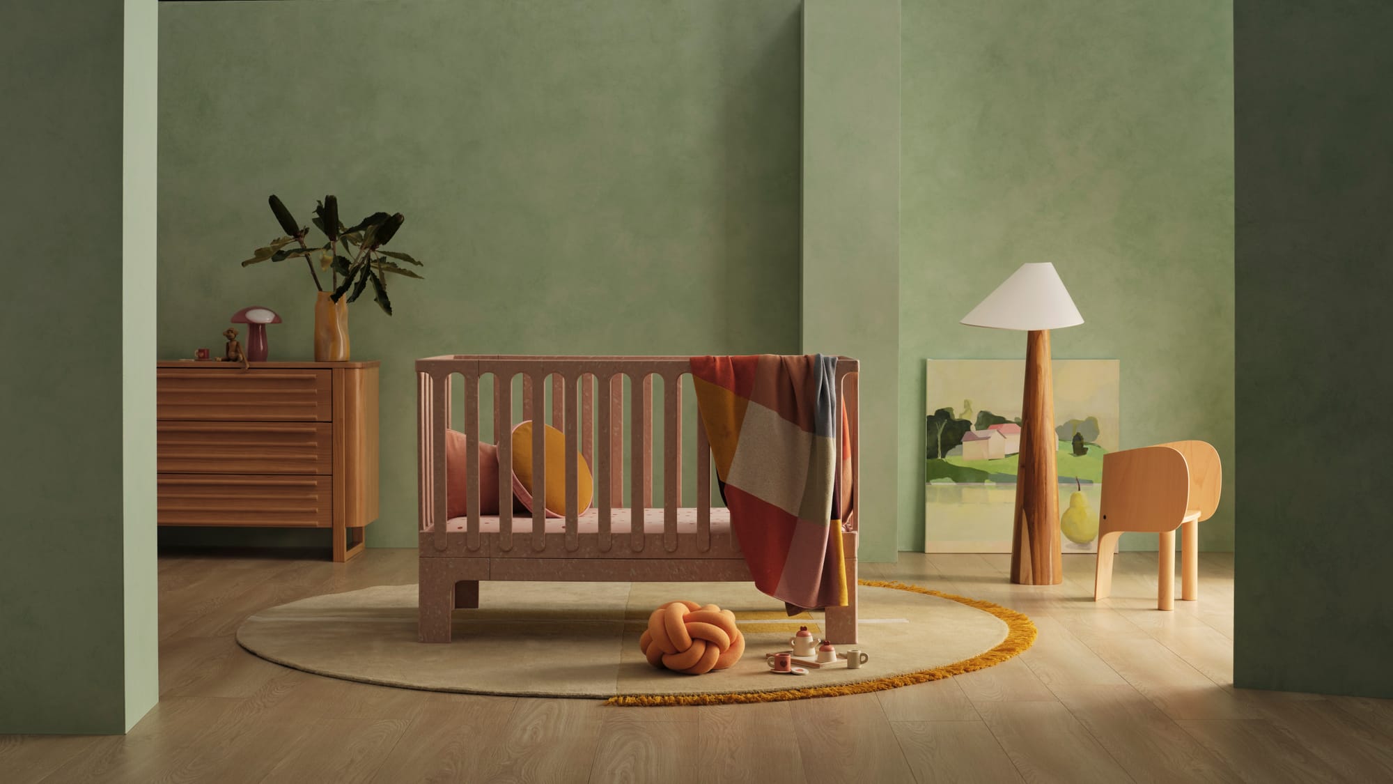 Archie Cot by Seena x Defy in Dusty Rose. Pink cot in room with green walls, timber floors and warm timber furnishings. 