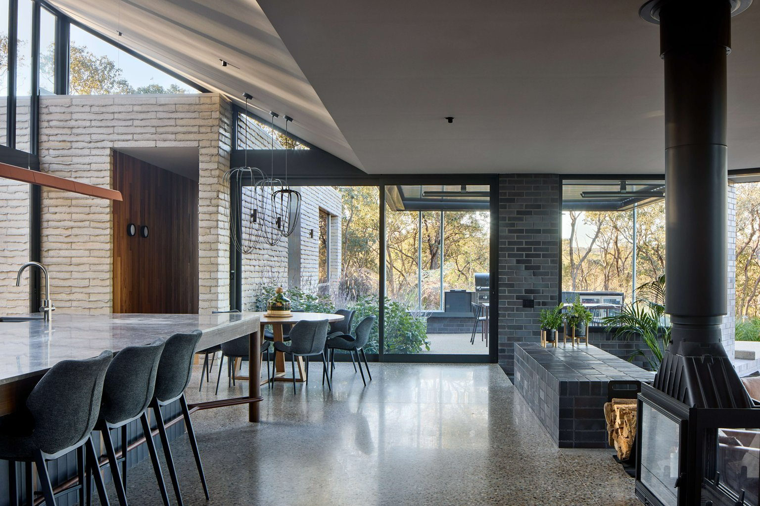 Korinda House by BENT Architecture. Photography by Tatjana Plitt. Open plan kitchen and dining area, with sunken living room, with polished concrete flooring throughout. 