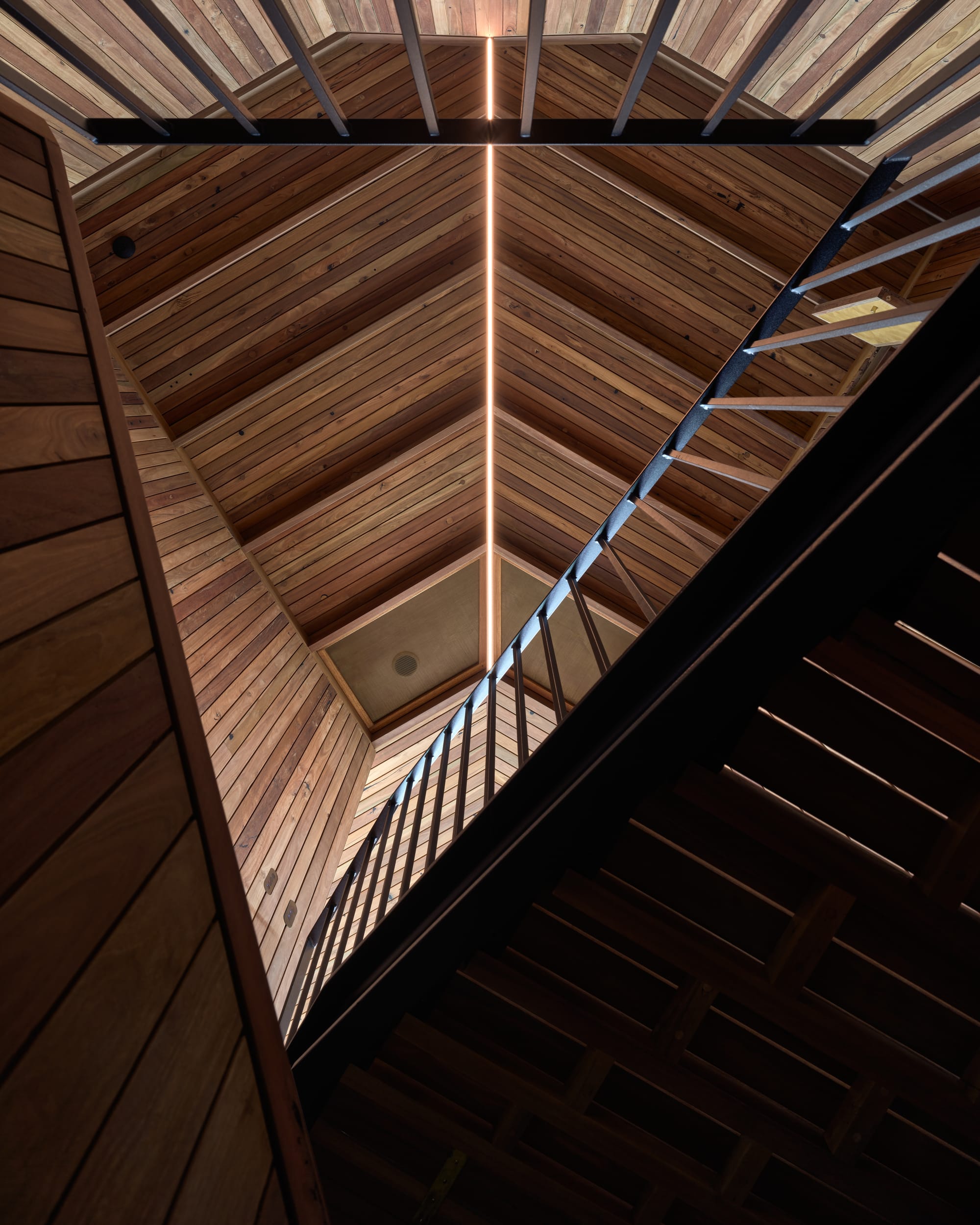 Cake House by Alexander Symes Architect. Photography by Barton Taylor. Low angle show of overlapping timber staircases and walkways, with pitched timber clad ceiling in background. 
