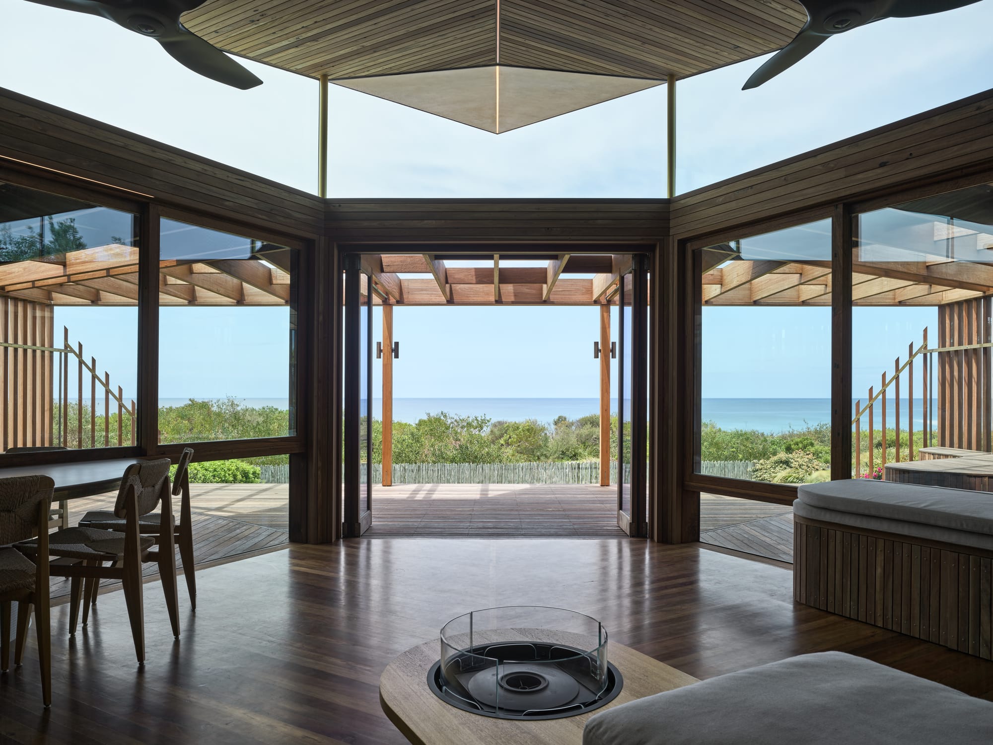 Cake House by Alexander Symes Architect. Photography by Barton Taylor. Open plan living and dining room with panoramic views of beach through glass rear facade.