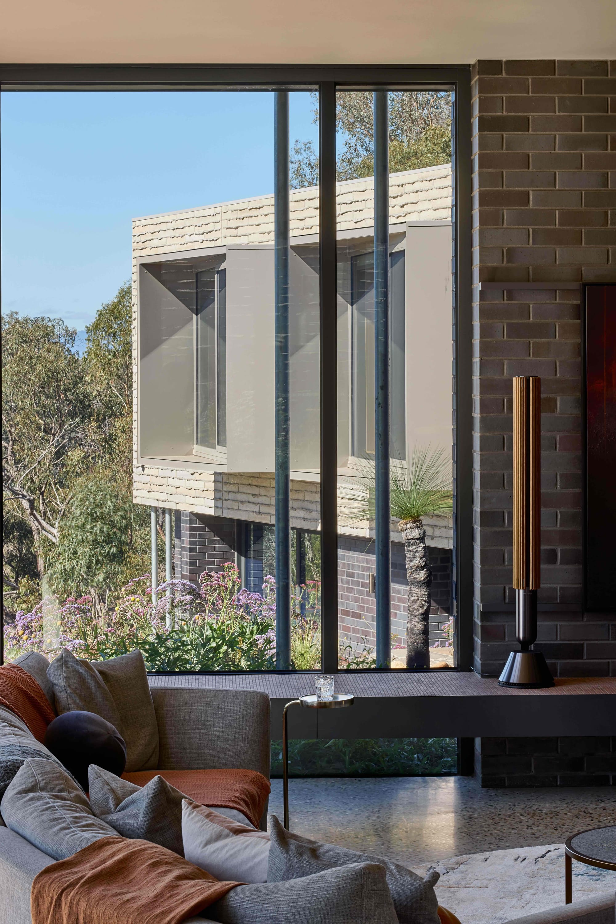 Korinda House by BENT Architecture. Photography by Tatjana Plitt. Full height window overlooking garden in living room, with a plinth running length of room. 
