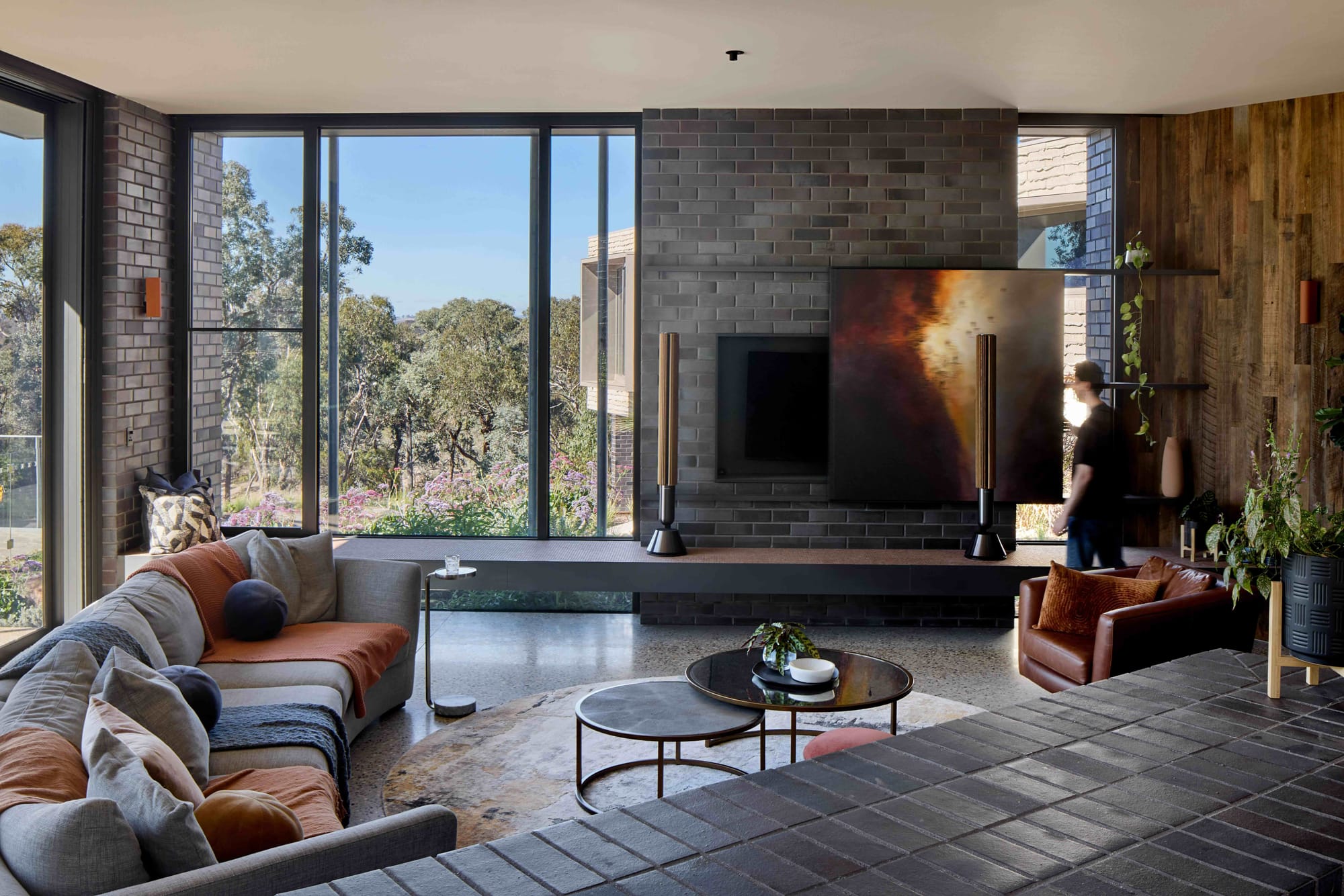 Korinda House by BENT Architecture. Photography by Tatjana Plitt. Living space with curved cry couch, timber walls and dark brick features. 