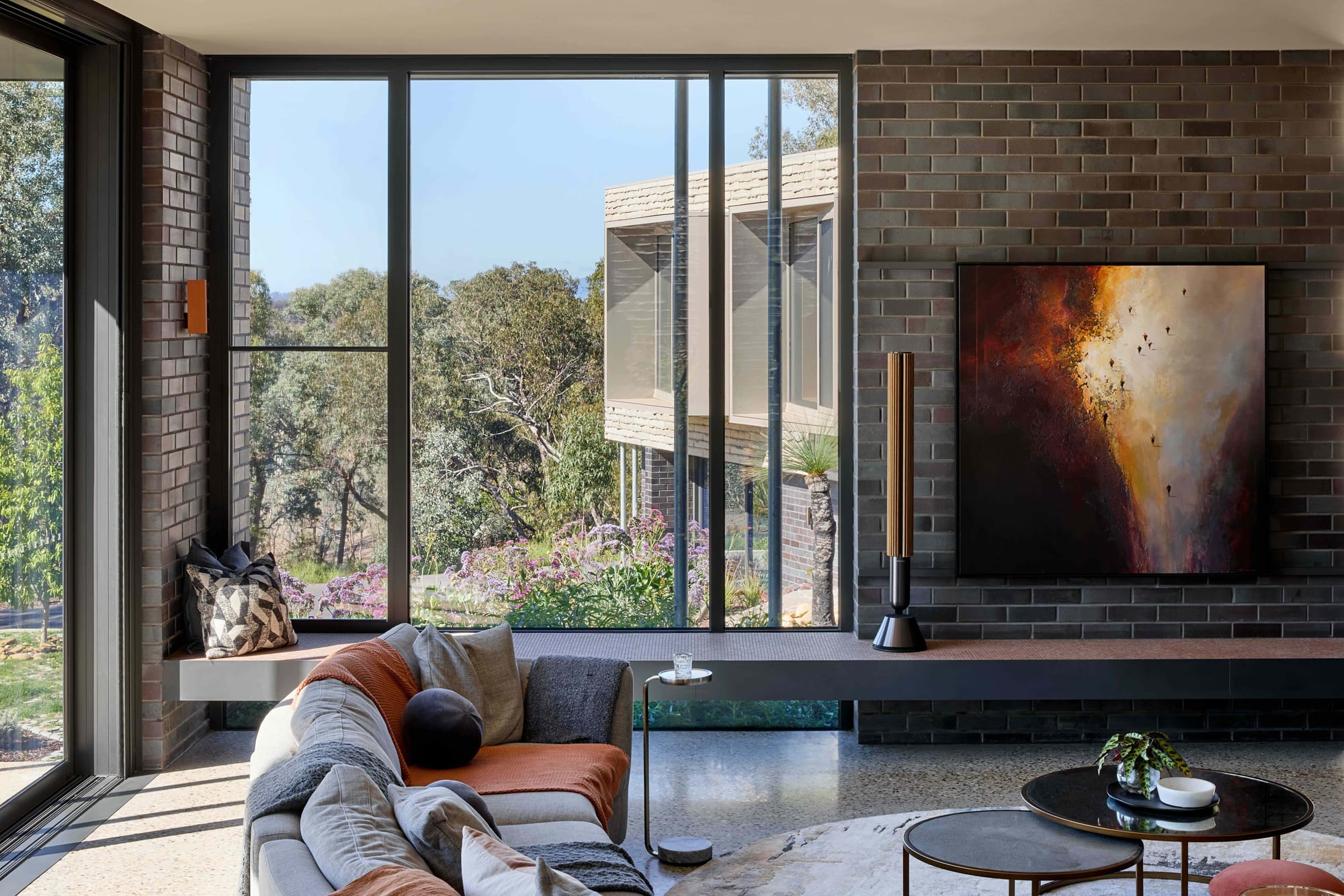 Korinda House by BENT Architecture. Photography by Tatjana Plitt. Living space with black brick walls and windows overlooking courtyard below. 