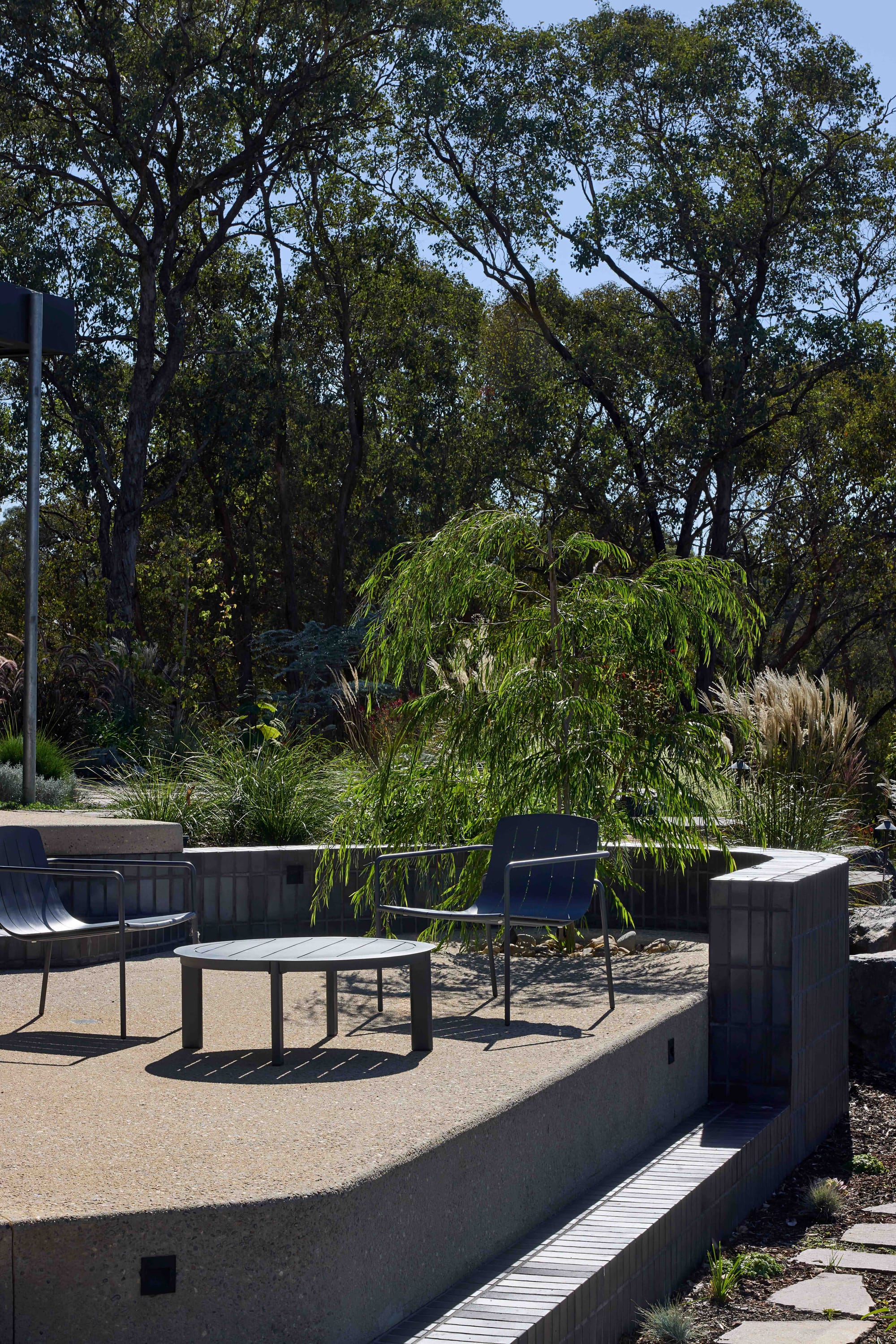 Korinda House by BENT Architecture. Photography by Tatjana Plitt. Outdoor elevated seating area with brick retaining wall. 