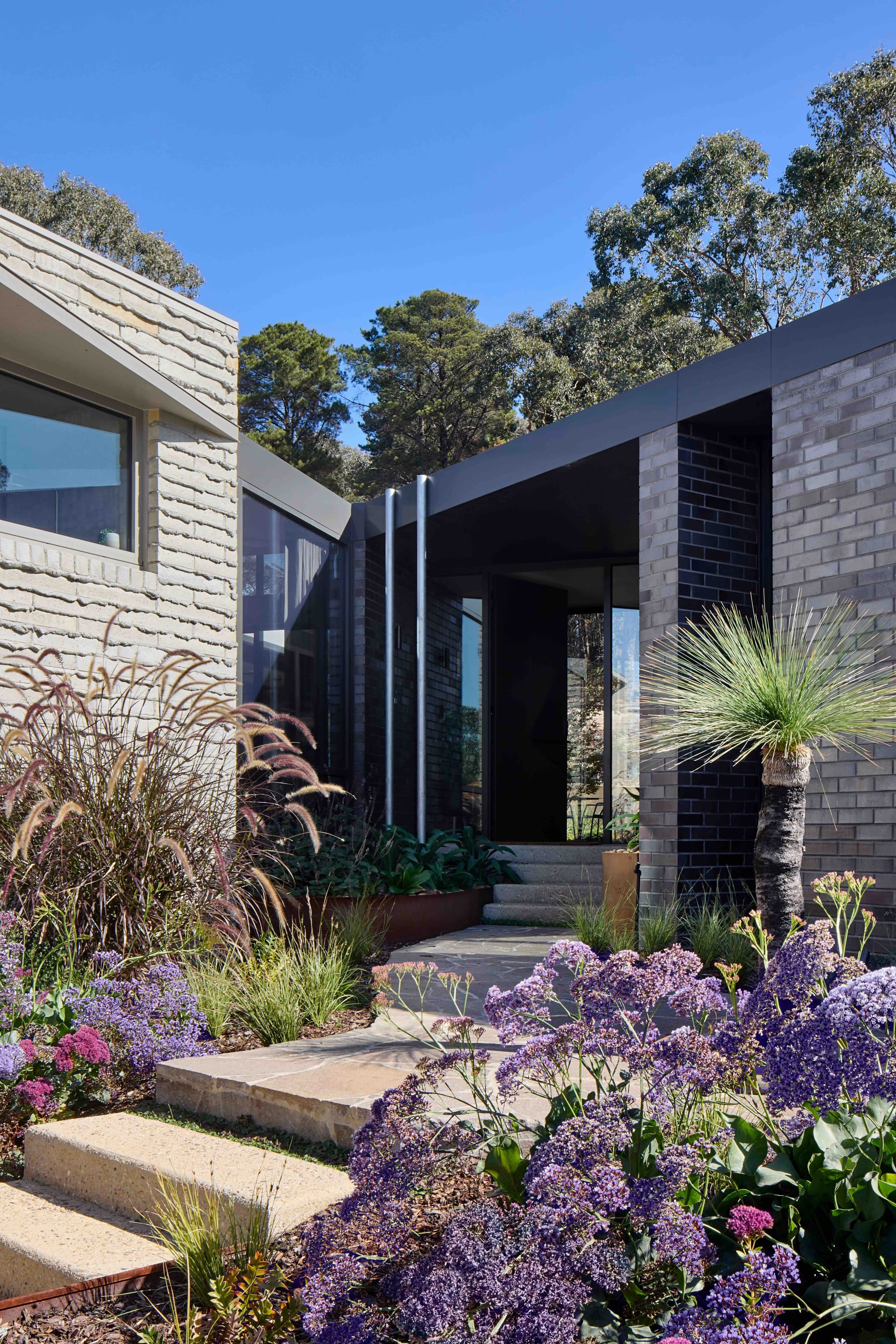 Korinda House by BENT Architecture. Photography by Tatjana Plitt. Stairs leading through native garden to home of dark brick and timbercrete.