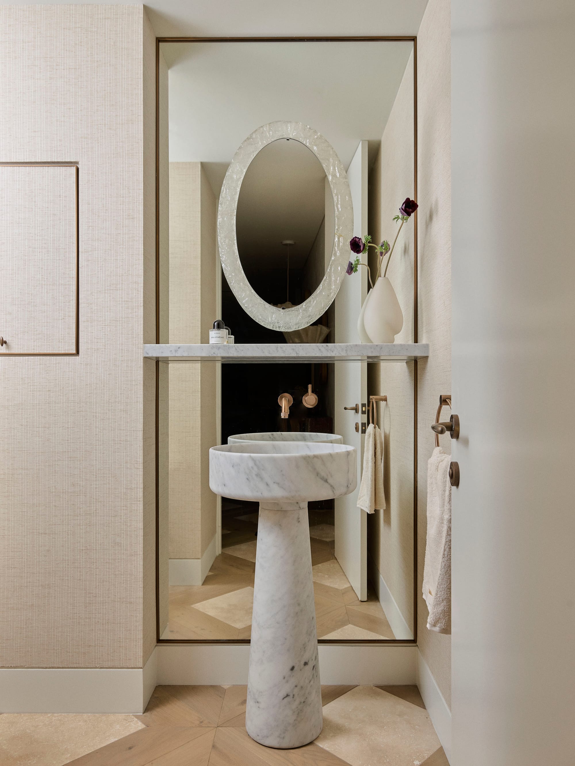 Bundarra Penthouse by Marylou Sobel Interior Design. Photography by Anson Smart. Bathroom with freestanding white marble sink and vanity in front of a full length mirror, with parquet timber and tile flooring. 