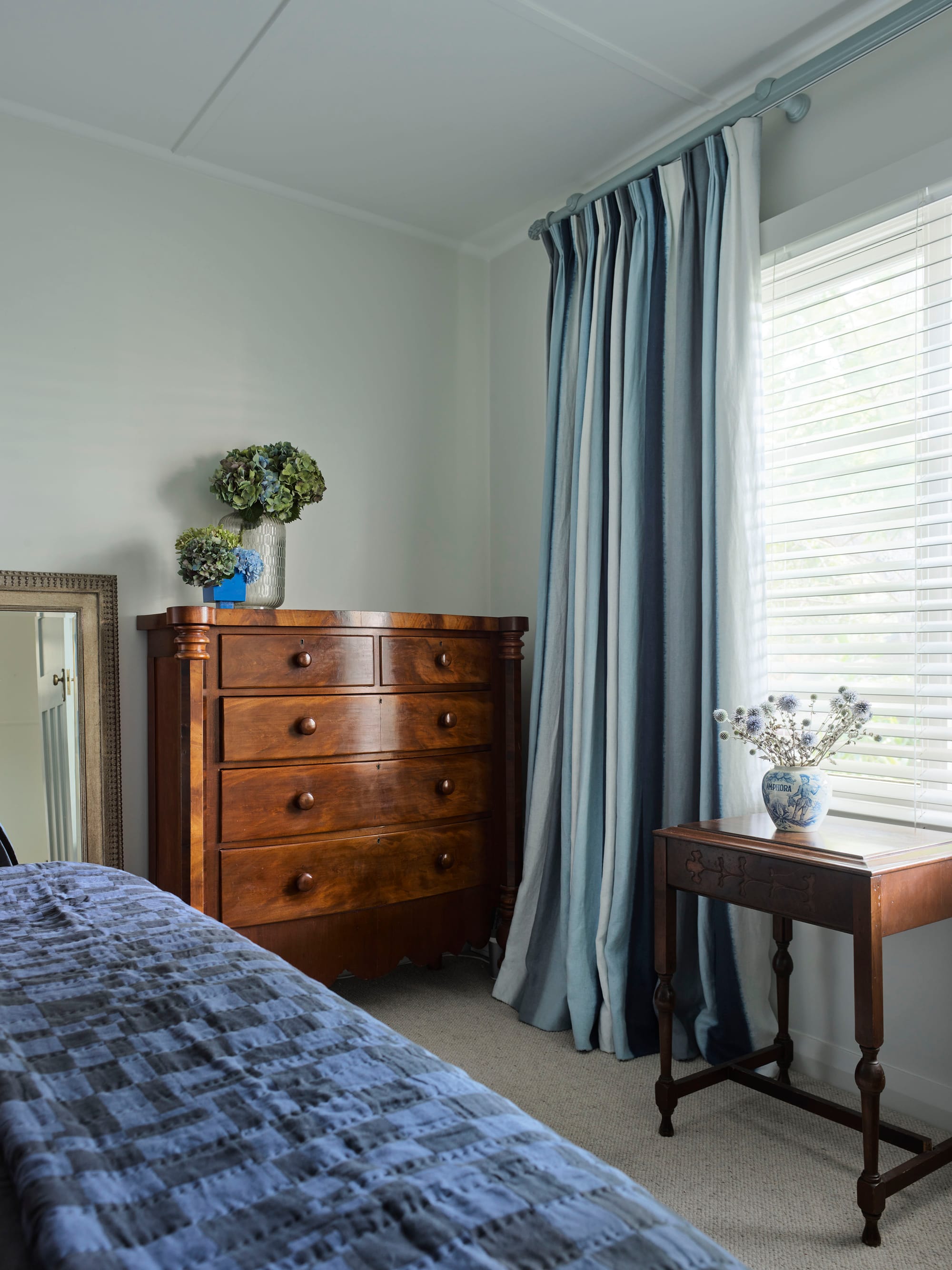 Ferris Street by Marylou Sobel Interior Design. Photography by Anson Smart. Bedroom with dark, timber, vintage dresser, bedside table under window and dark bedspread on bed. 