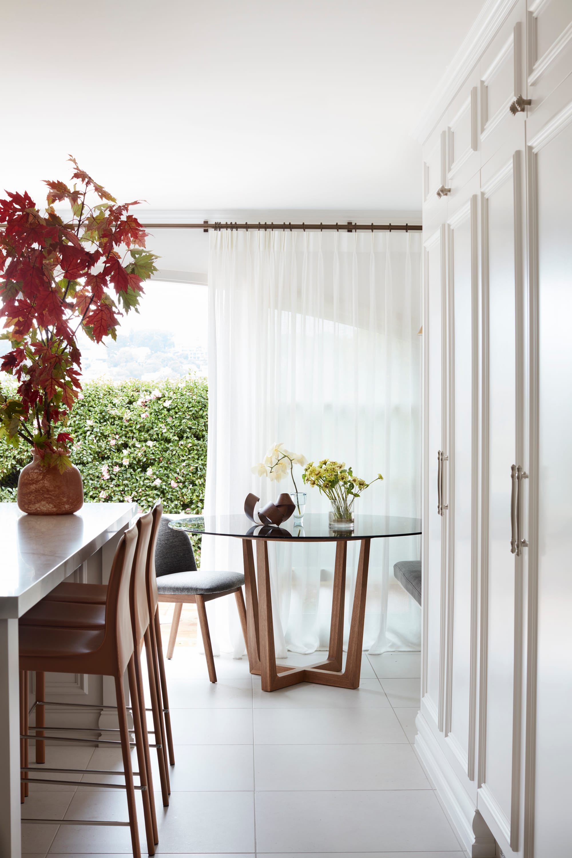 Marathon Road by Marylou Sobel Interior Design. Photography by Prue Ruscoe. Open plan kitchen and dining space with round dining table, stools at island bench and full height white cabinetry on right handside. 