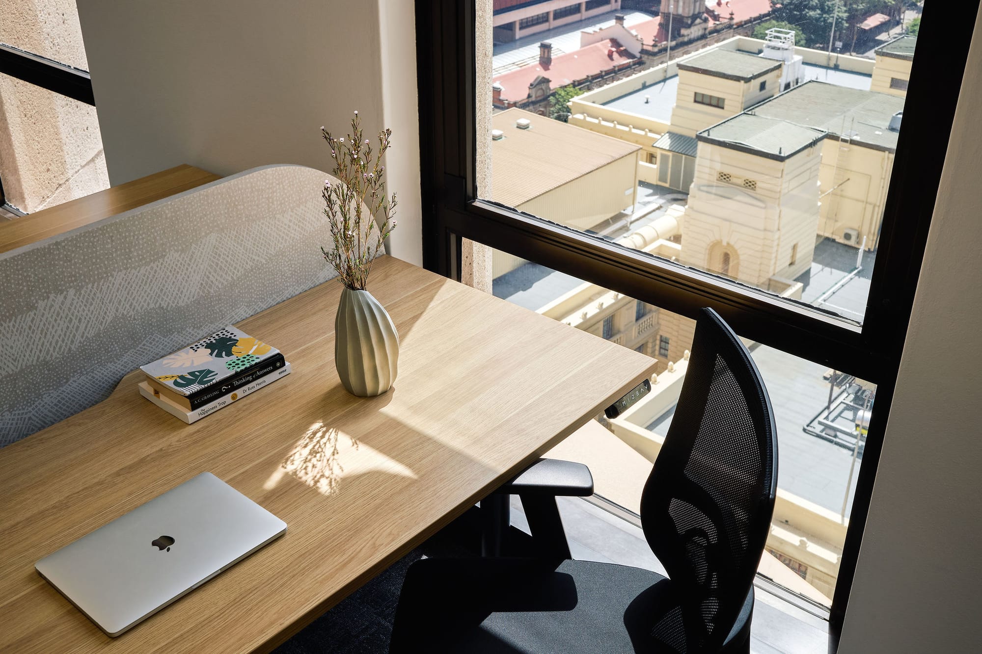 Project Kubo by M&E Interiors.  At home office set up with small timber desk with black chair and laptop, next to full height window overlooking city views below. 