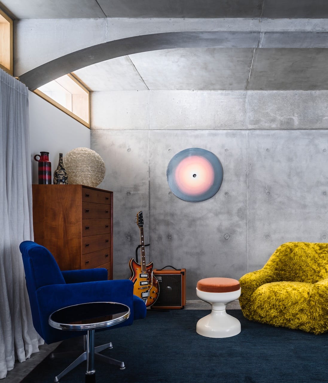 Corbel House by Nick Bell Architects. Photography by Justin Alexander. Bedroom with concrete walls and ceiling, electric blue and mustard yellow armchairs and a timber cabinet. 