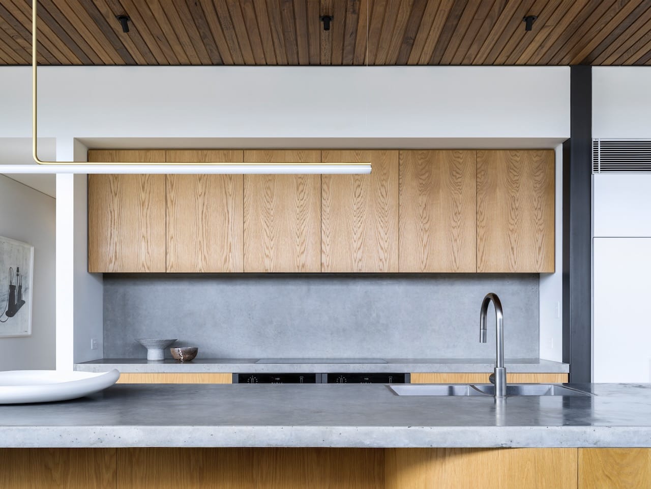 Corbel House by Nick Bell Architects. Photography by Justin Alexander. Kitchen with concrete countertop and splashback, timber cabinetry, white walls and timber paneled ceiling. 