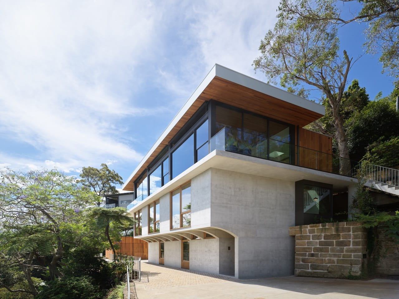 Corbel House by Nick Bell Architects. Photography by Justin Alexander. Facade of three story home with concrete lower floors and glass upper floor.