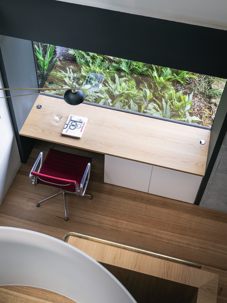 Corbel House by Nick Bell Architects. Photography by Justin Alexander. Aerial view of study space with timber desk, timber floors, magenta office chair and window overlooking garden. 