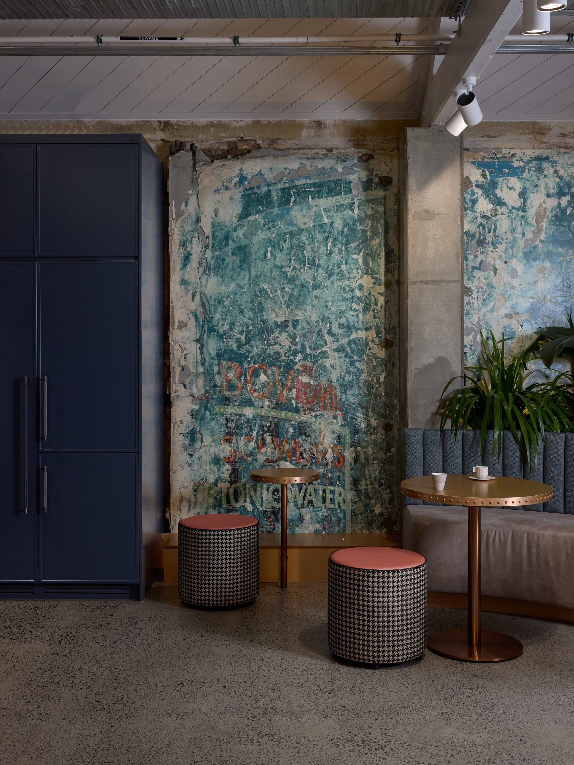 Project Kalakal by M&E Interiors. Office space with white rounded office pods, concrete flooring, blue abstract wallpaper and purple LED lighting. 