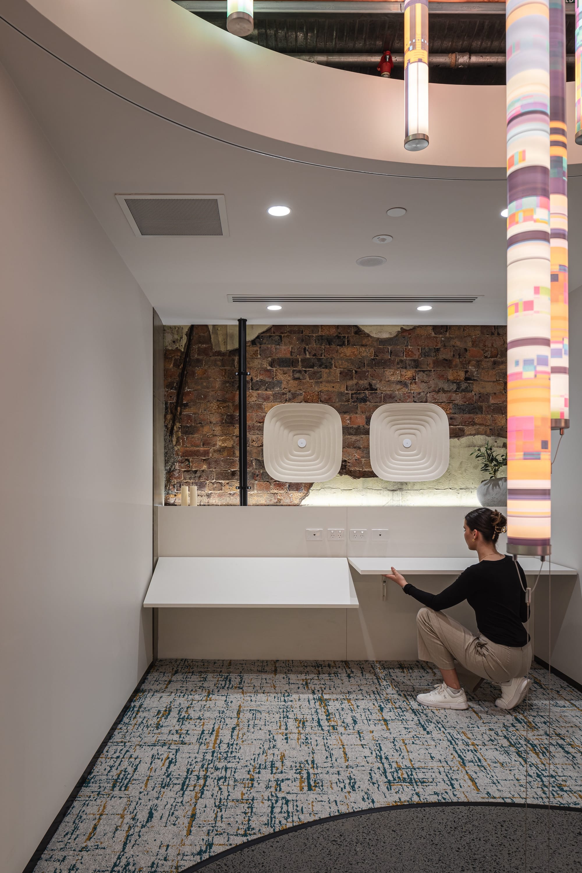 Project Kalakal by M&E Interiors. Office space with white rounded office pods, concrete flooring, blue abstract wallpaper and purple LED lighting. 