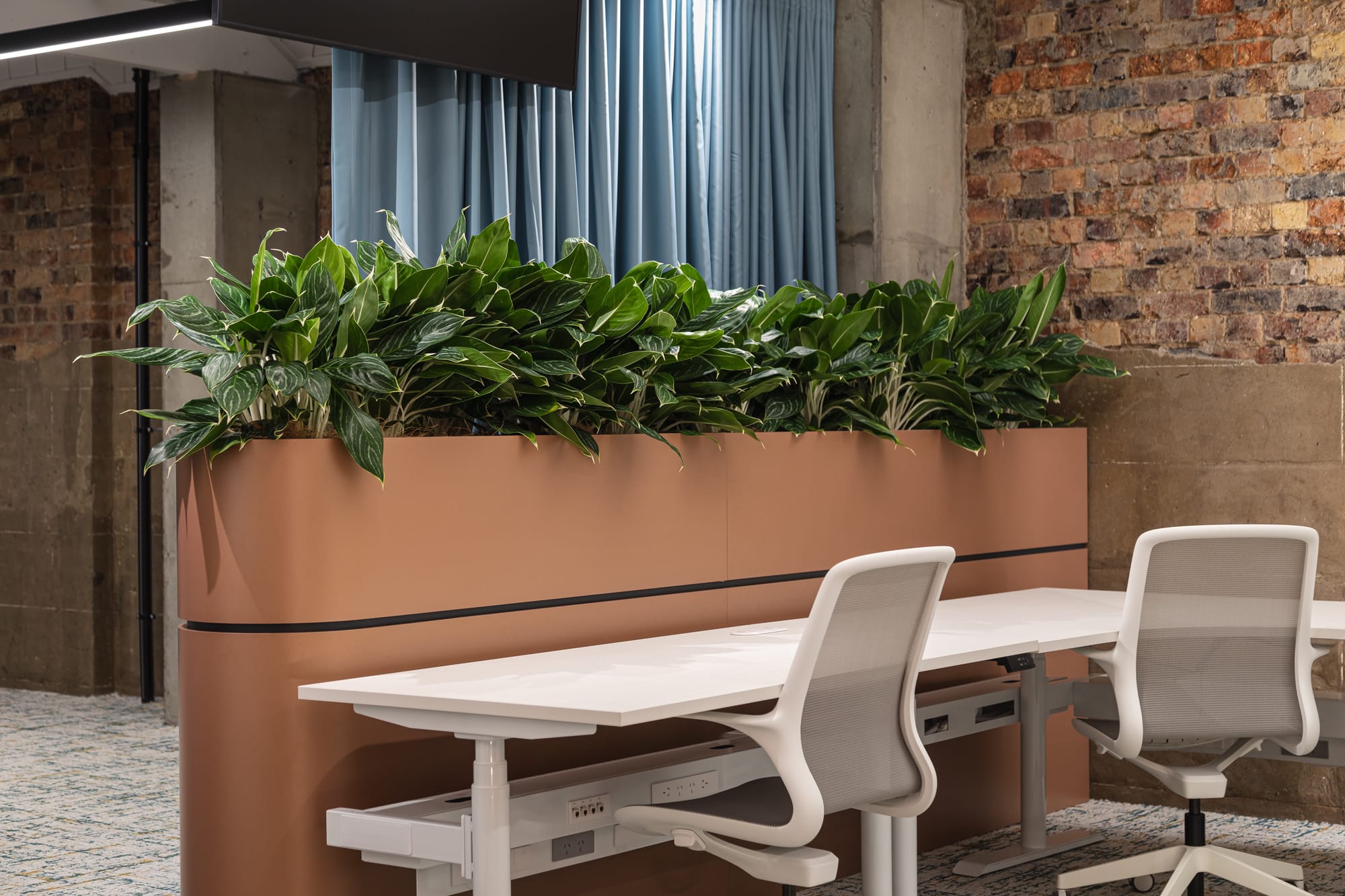 Project Kalakal by M&E Interiors. Office space with white rounded office pods, concrete flooring, blue abstract wallpaper and purple LED lighting. 