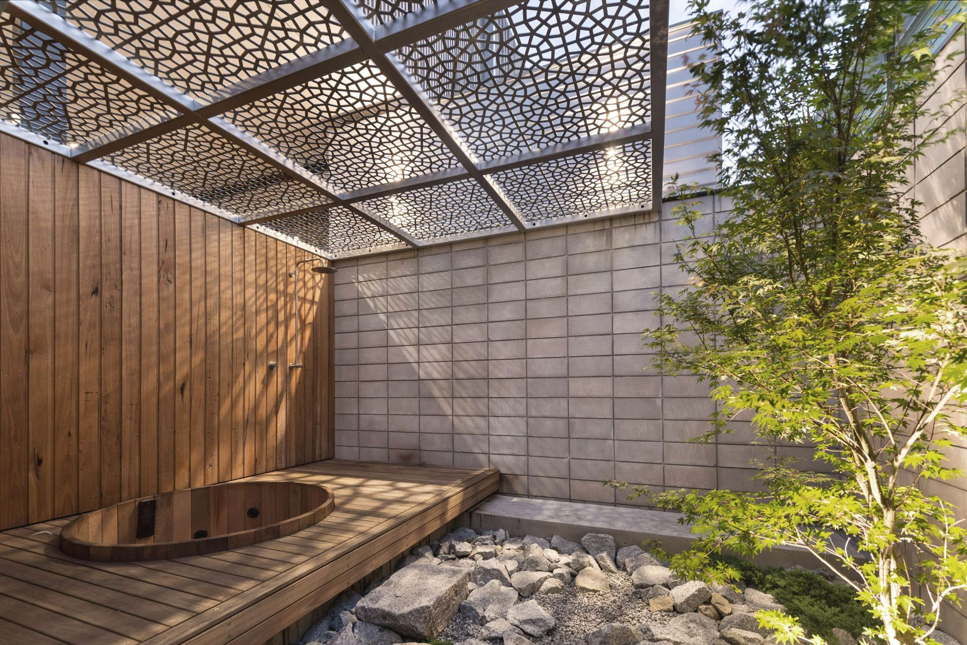 Estelle Street Residence by pcg. Architects. Photography by Matthew Mallett. Japanese-inspired courtyard with timber patio and sunken timber paneled bath, rock garden and laser-cut patterned awning. 