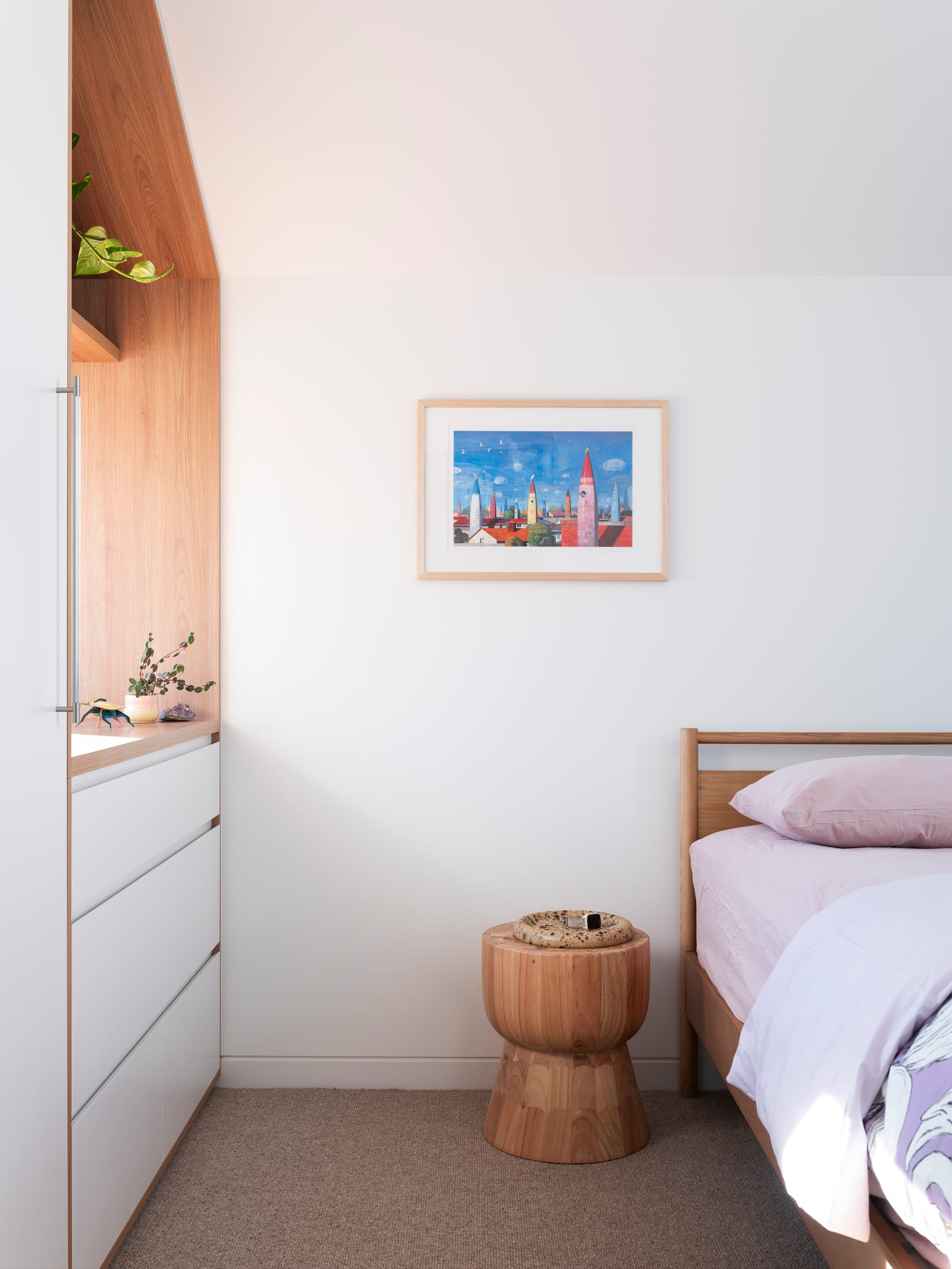 Merrilands by BIJL Architecture. Photography by Tom Ferguson. Bedroom with beige carpets, white walls and integrated storage and timber bedframe with pastel pink and purple bedding. 